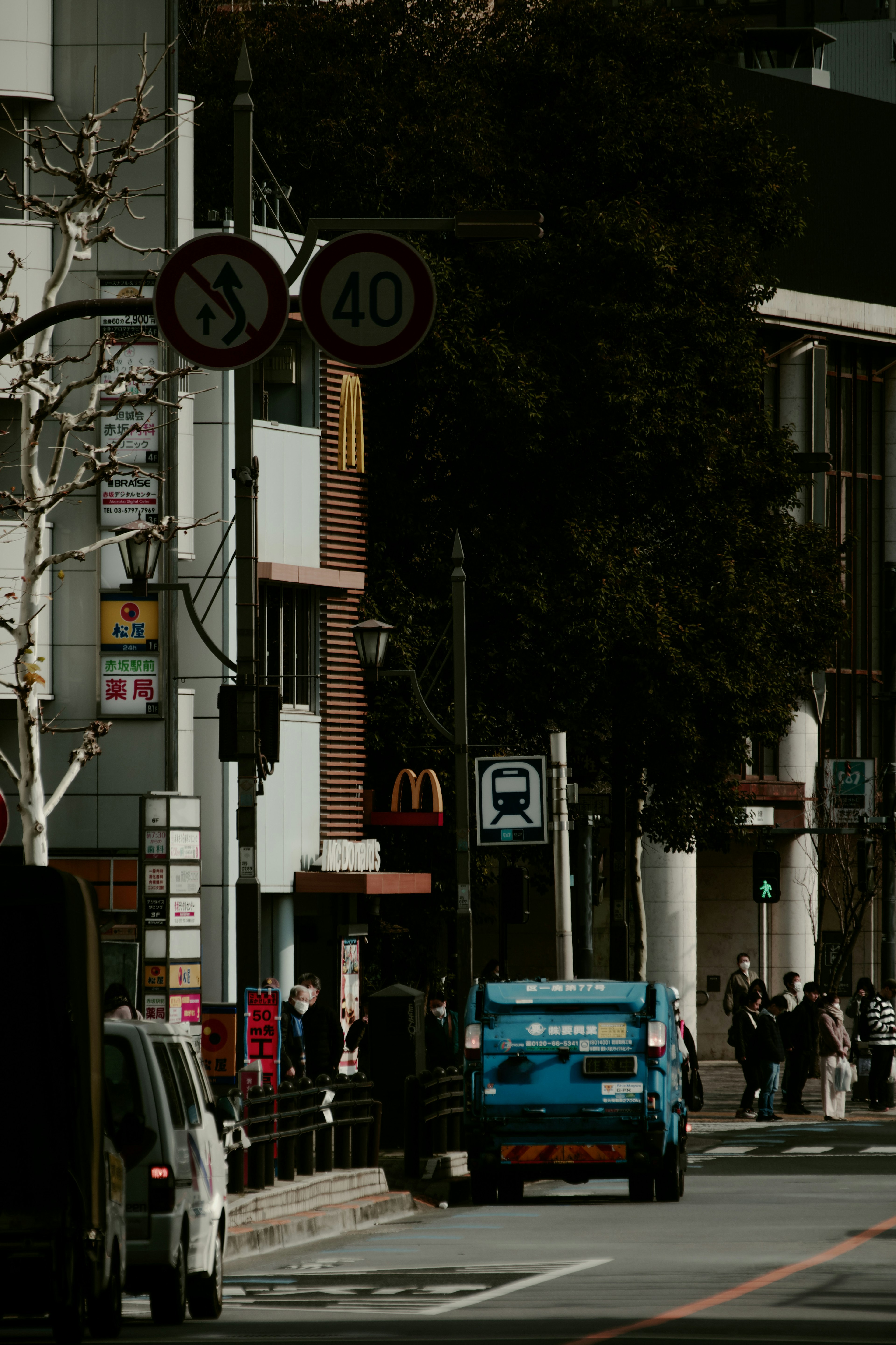 繁華街にあるマクドナルドの看板と青い車が見える通りの風景