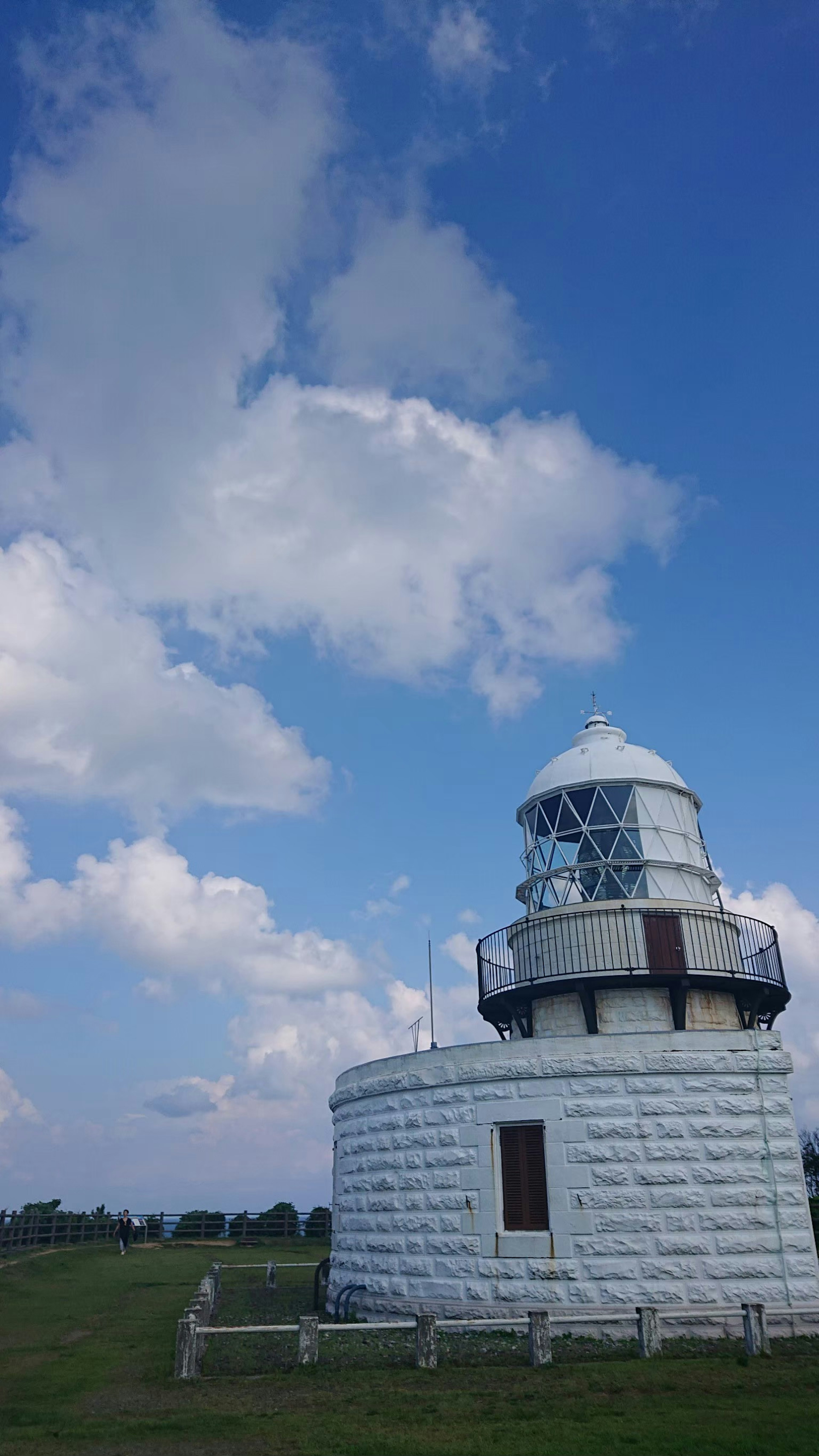 Edificio de faro blanco bajo un cielo azul con nubes