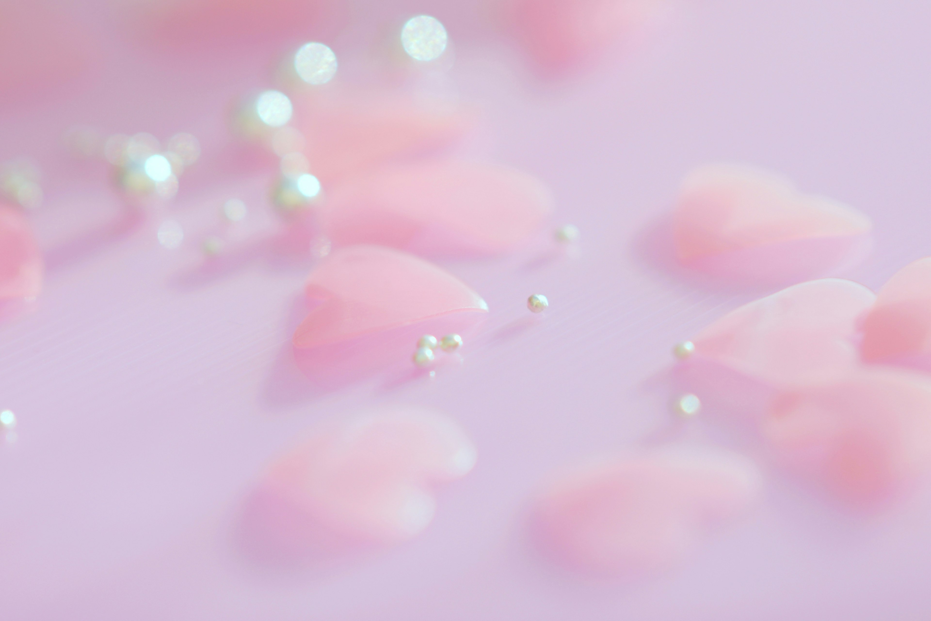 Décorations en forme de cœur rose pâle éparpillées avec des perles sur un fond clair