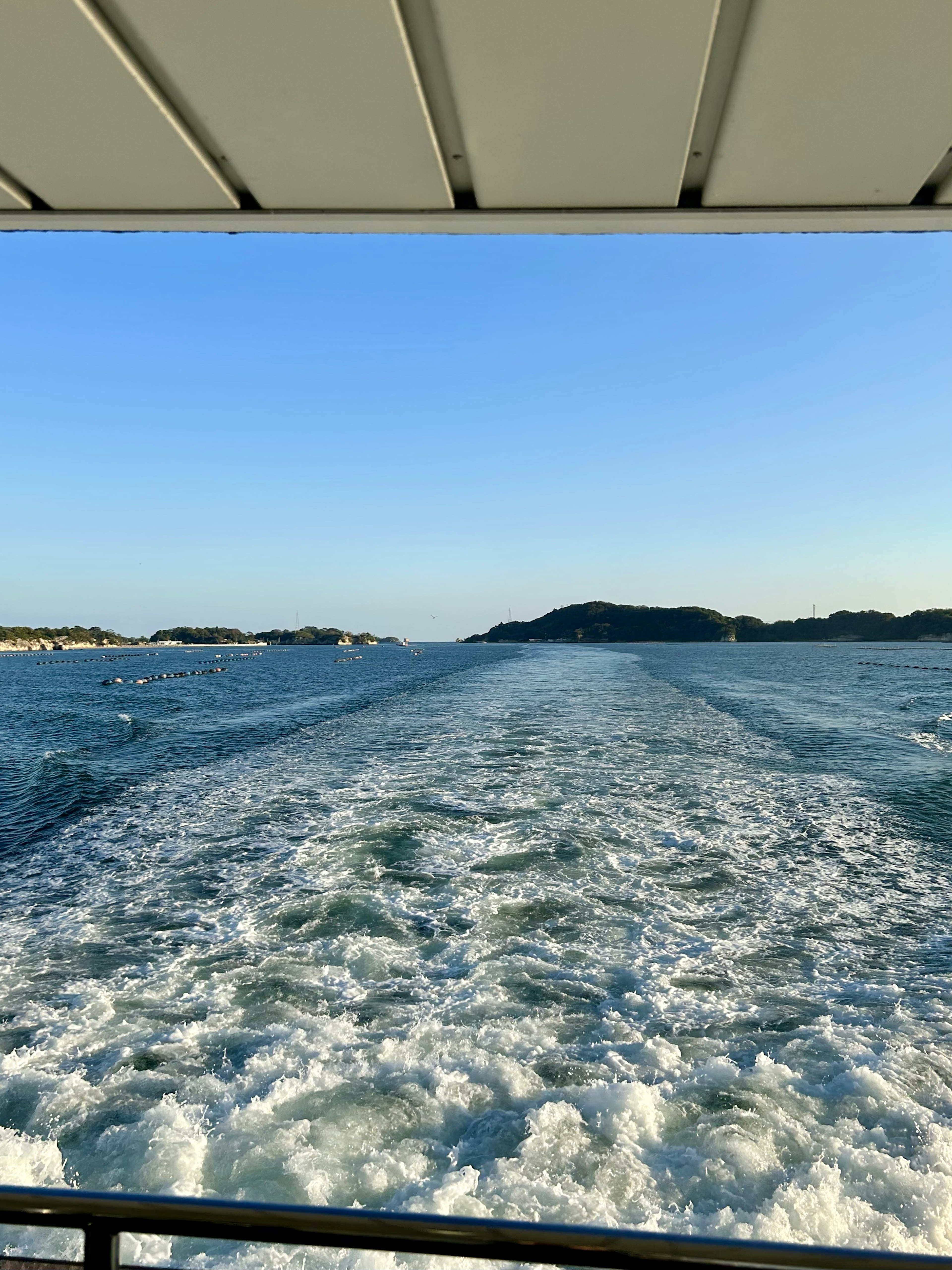 Scenic view of the ocean with boat wake and distant islands