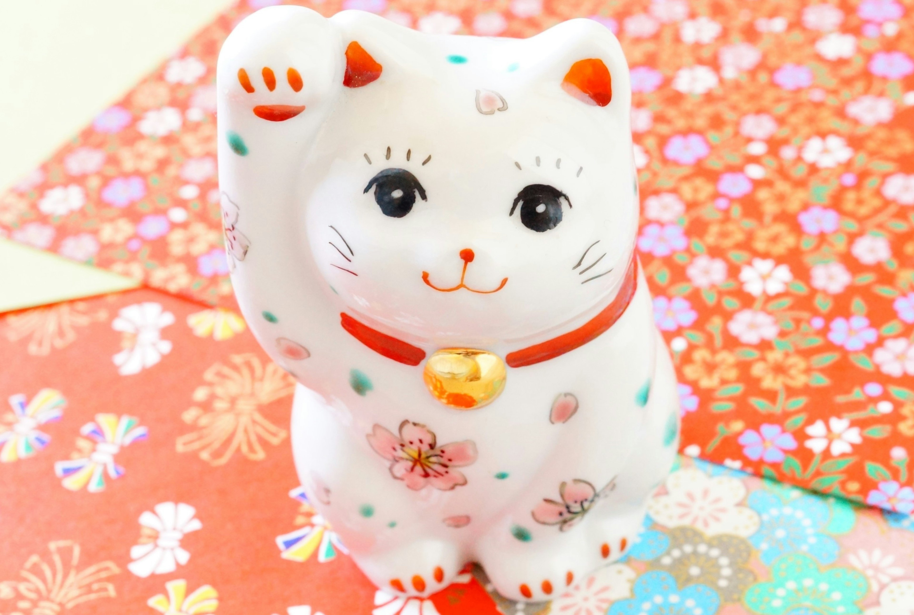 White lucky cat figurine with floral patterns on a colorful background