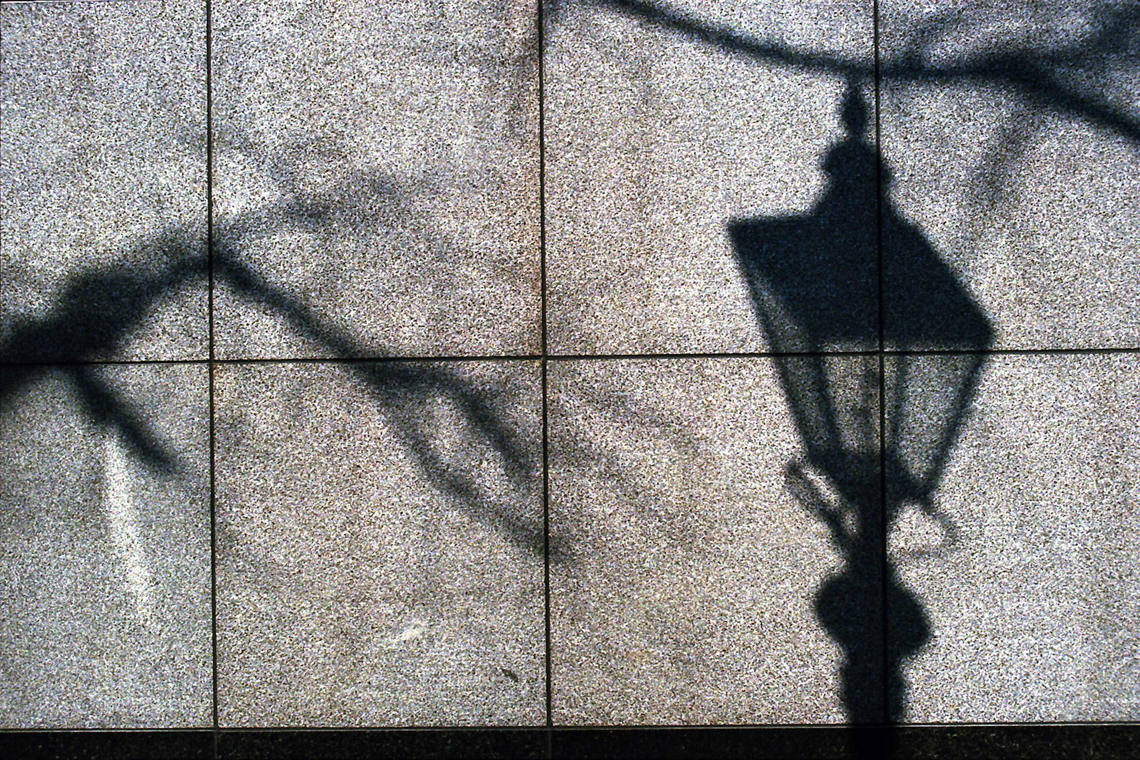 Silueta de una farola proyectando sombra en una pared texturizada