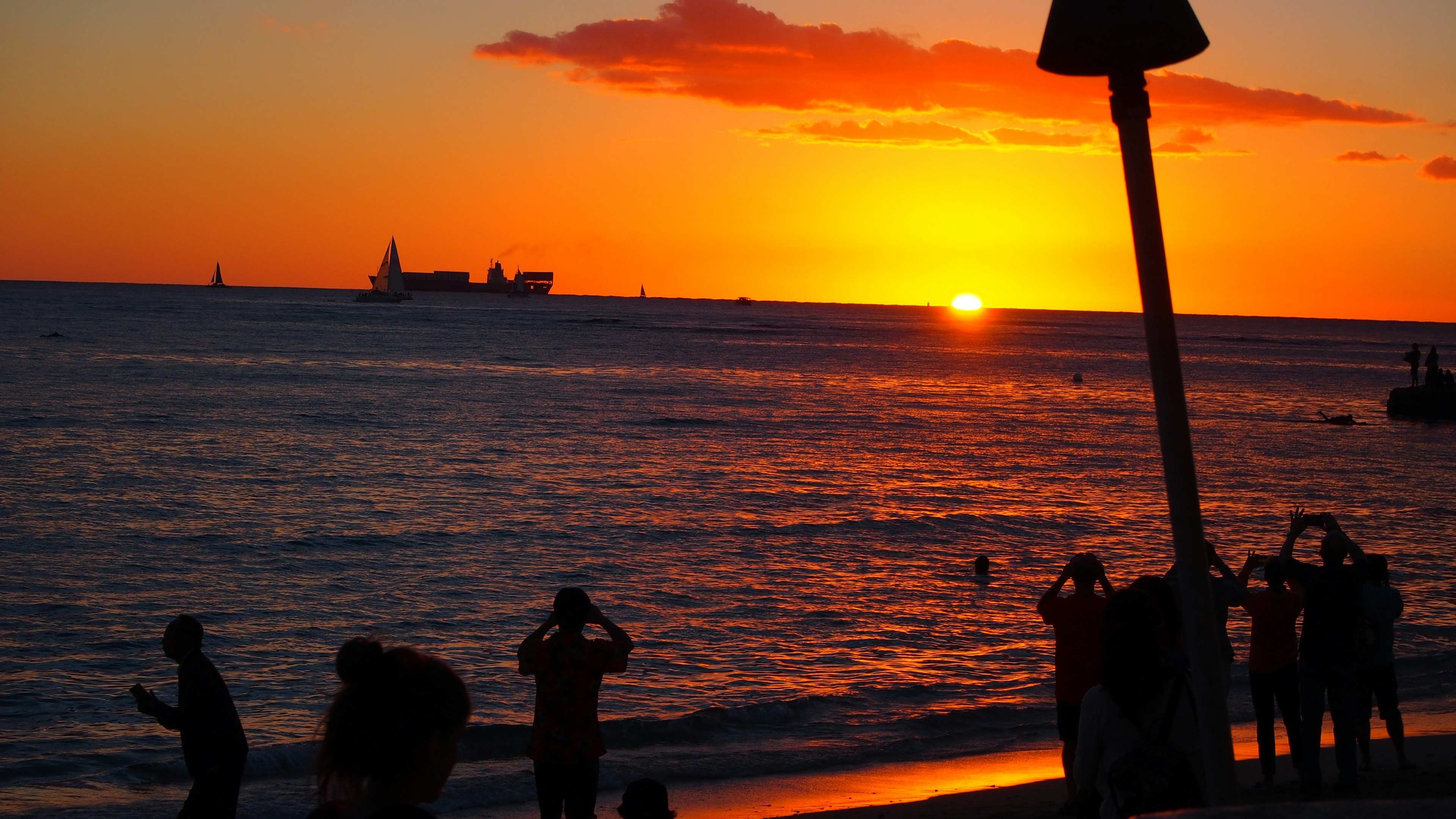 海岸での夕日を背景にした人々のシルエット