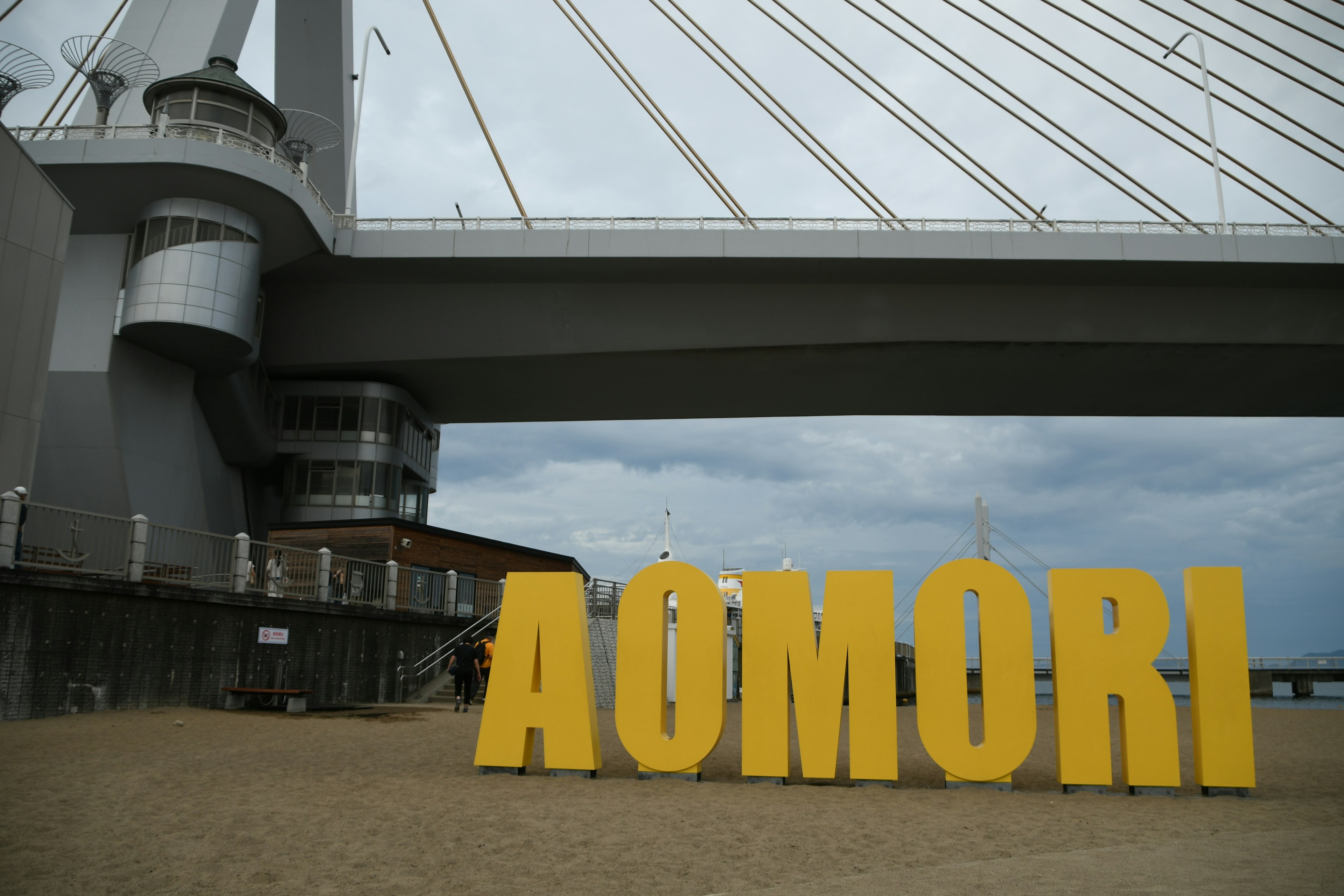 Großes gelbes Schild mit AOMORI und einer Brücke im Hintergrund