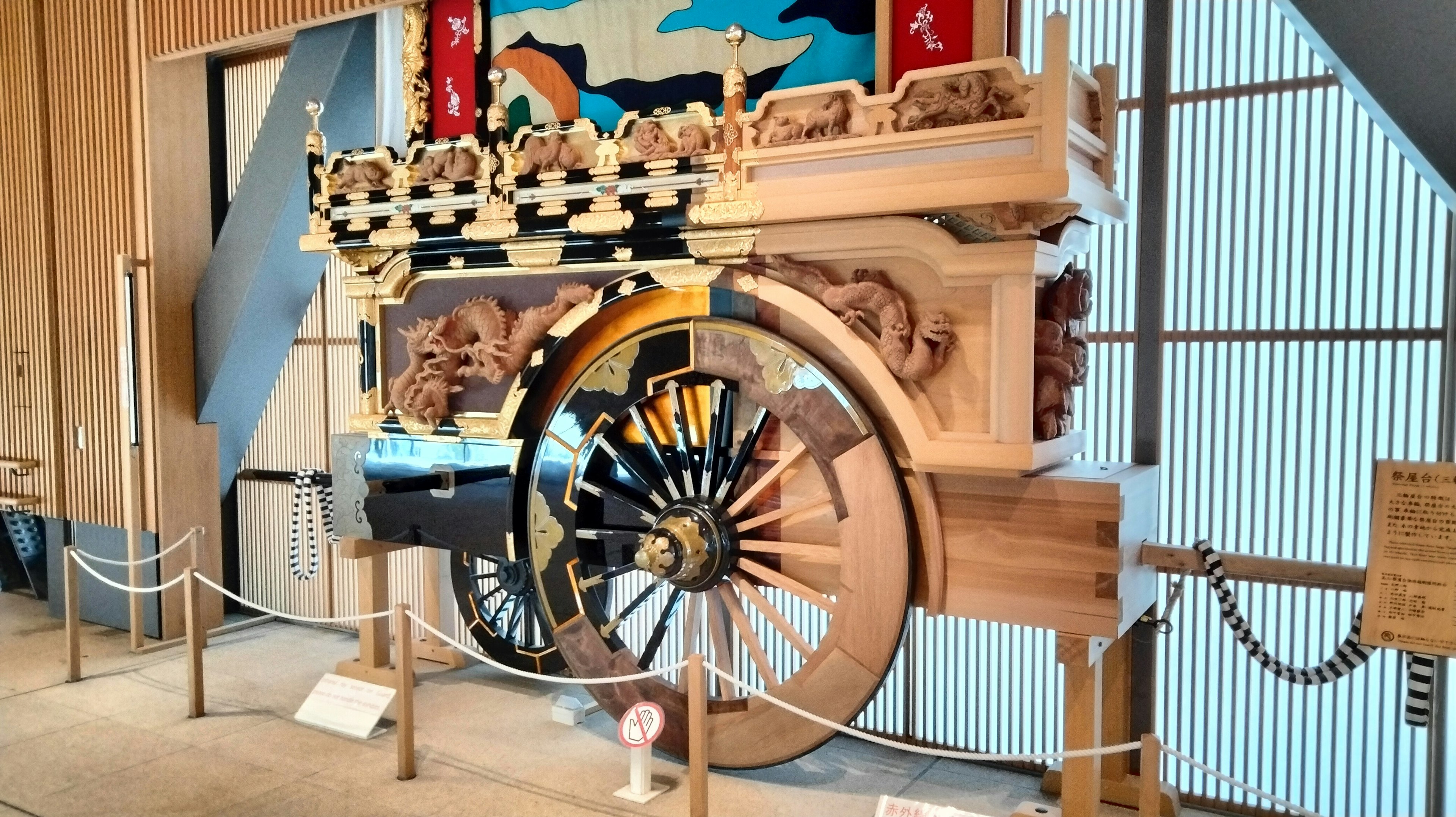 Traditional wooden cart with decorative wheel displayed indoors