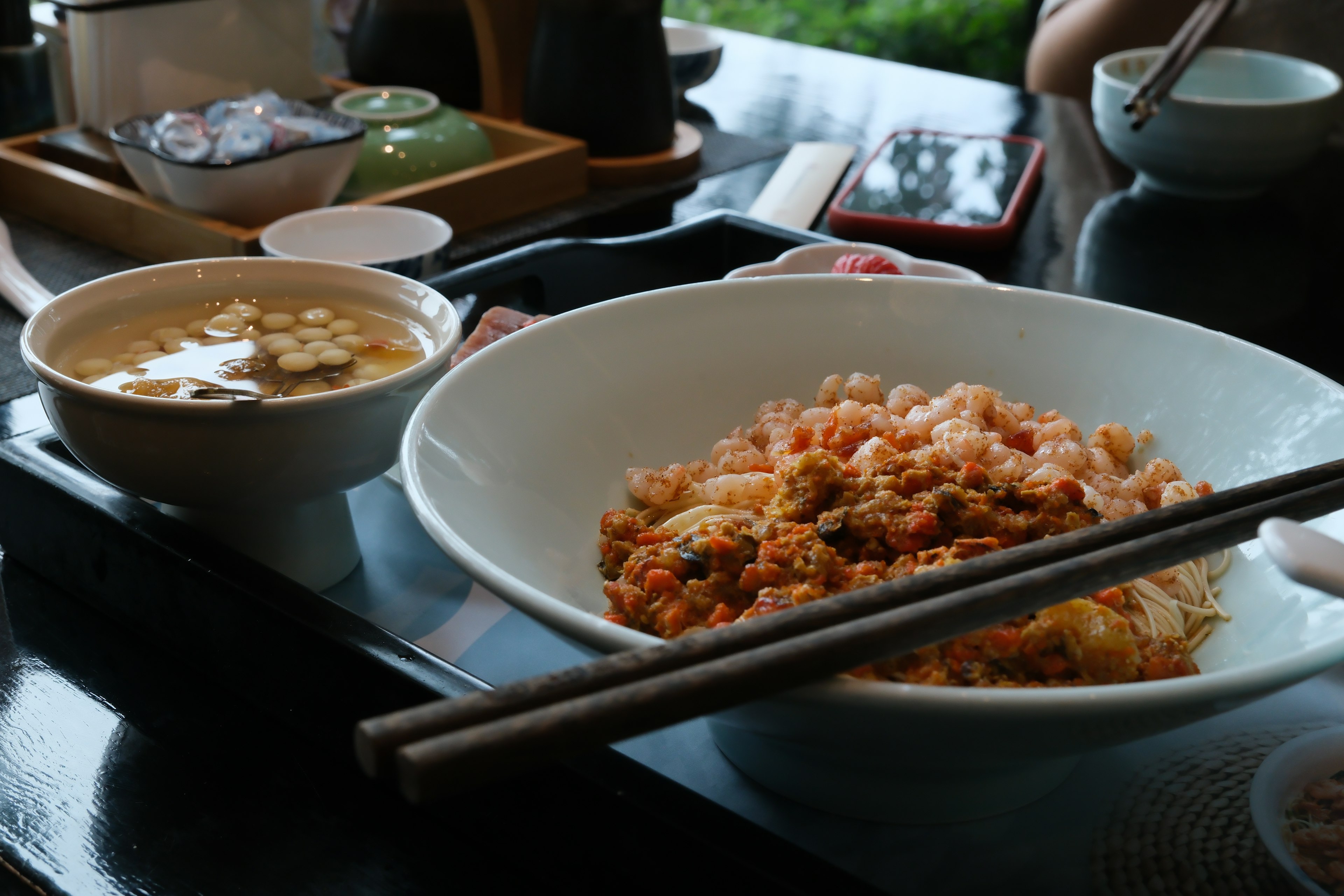 Colorful rice dish with assorted ingredients and soup on the table