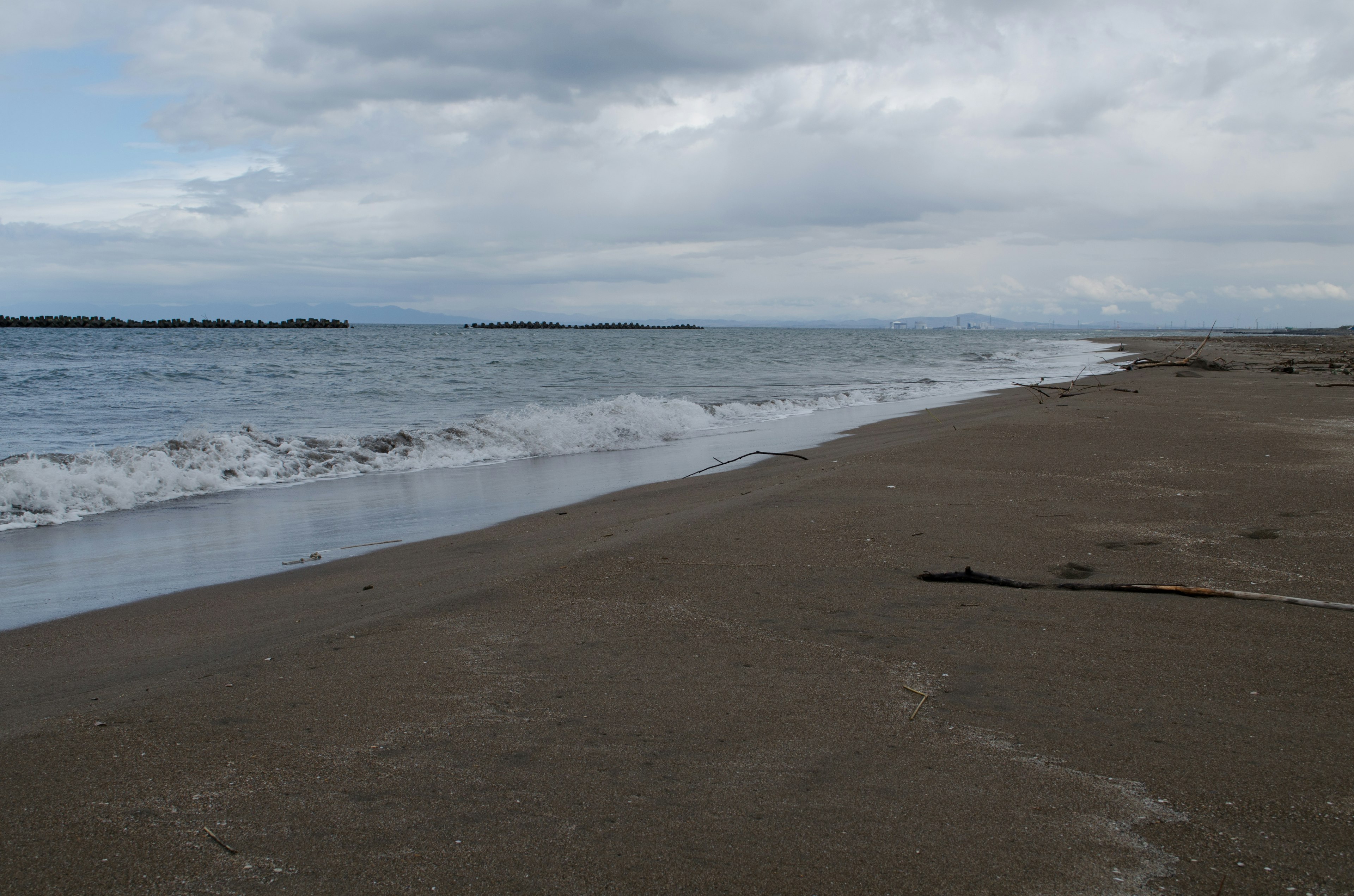 Pemandangan pantai berpasir yang indah dengan ombak lembut dan langit mendung