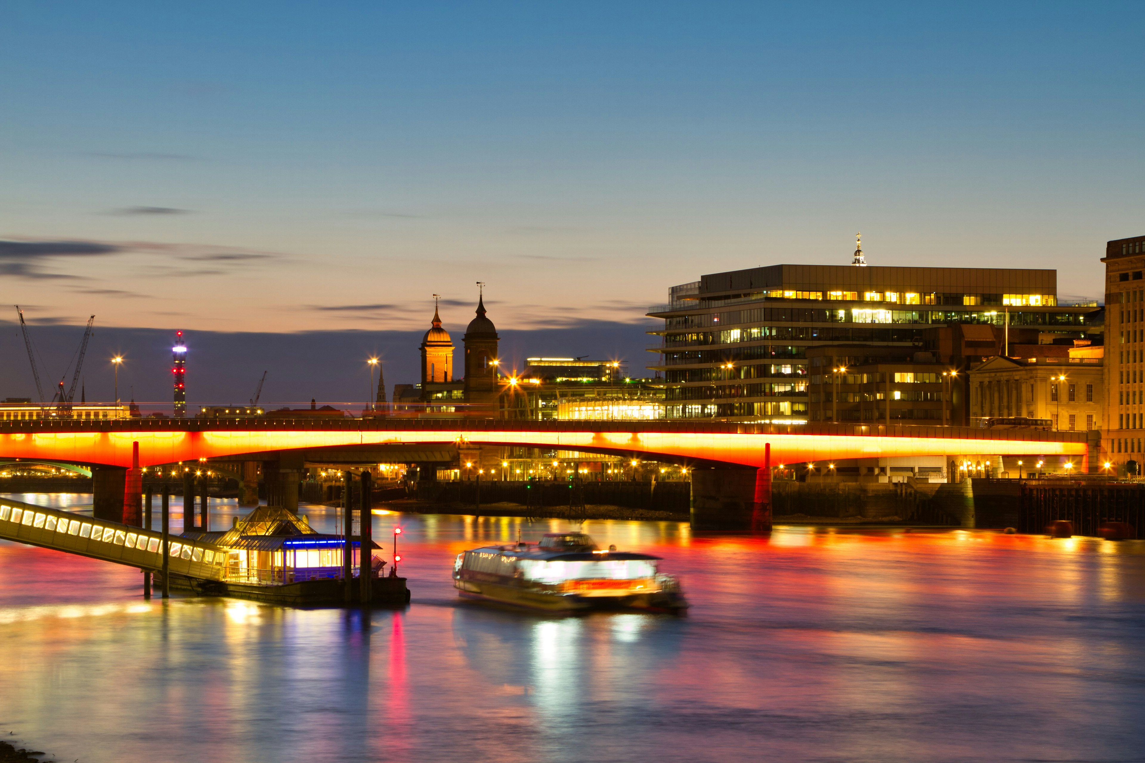 Evening view of the River Thames with illuminated bridge and city skyline