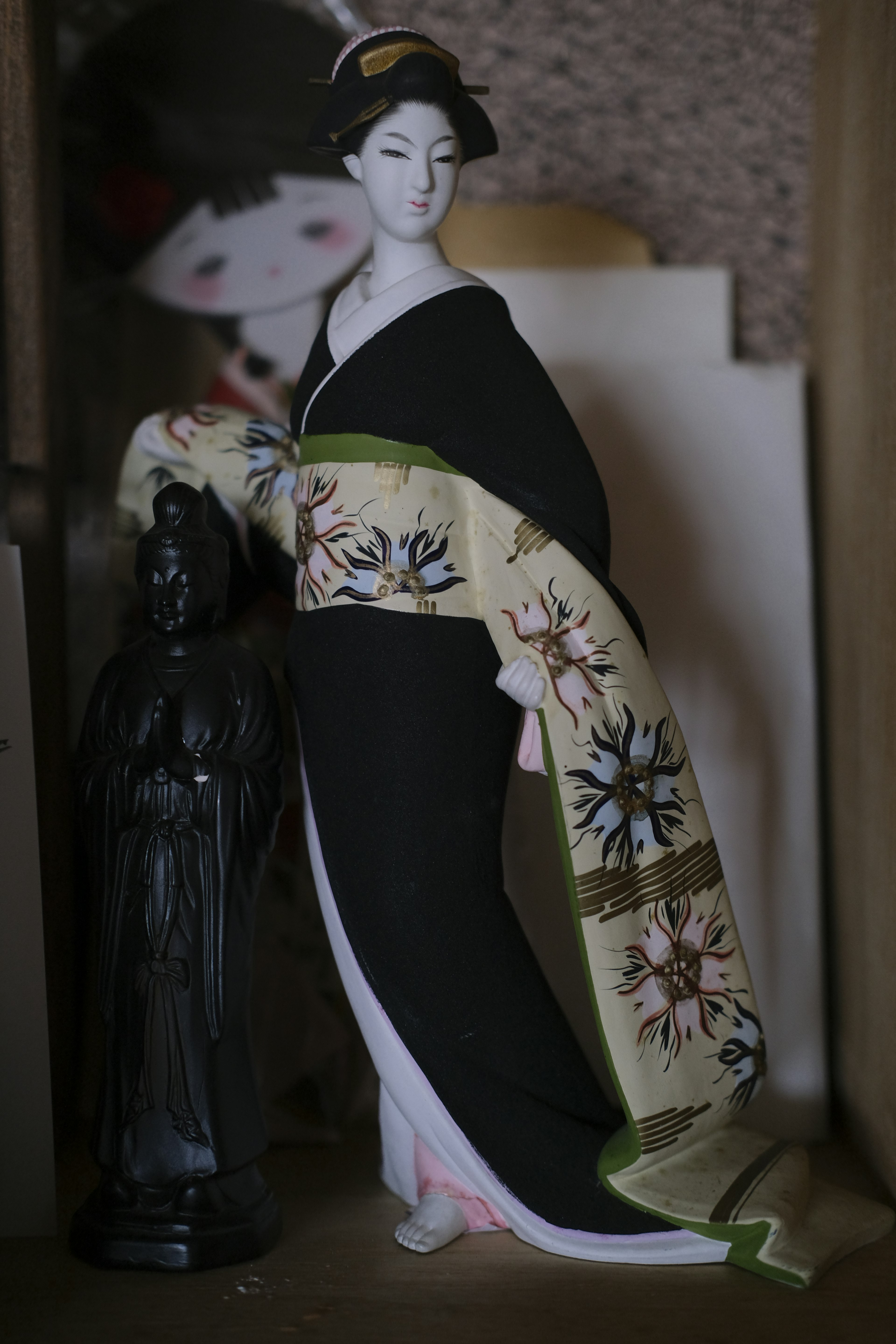 A doll wearing a black kimono holding a beautiful scarf