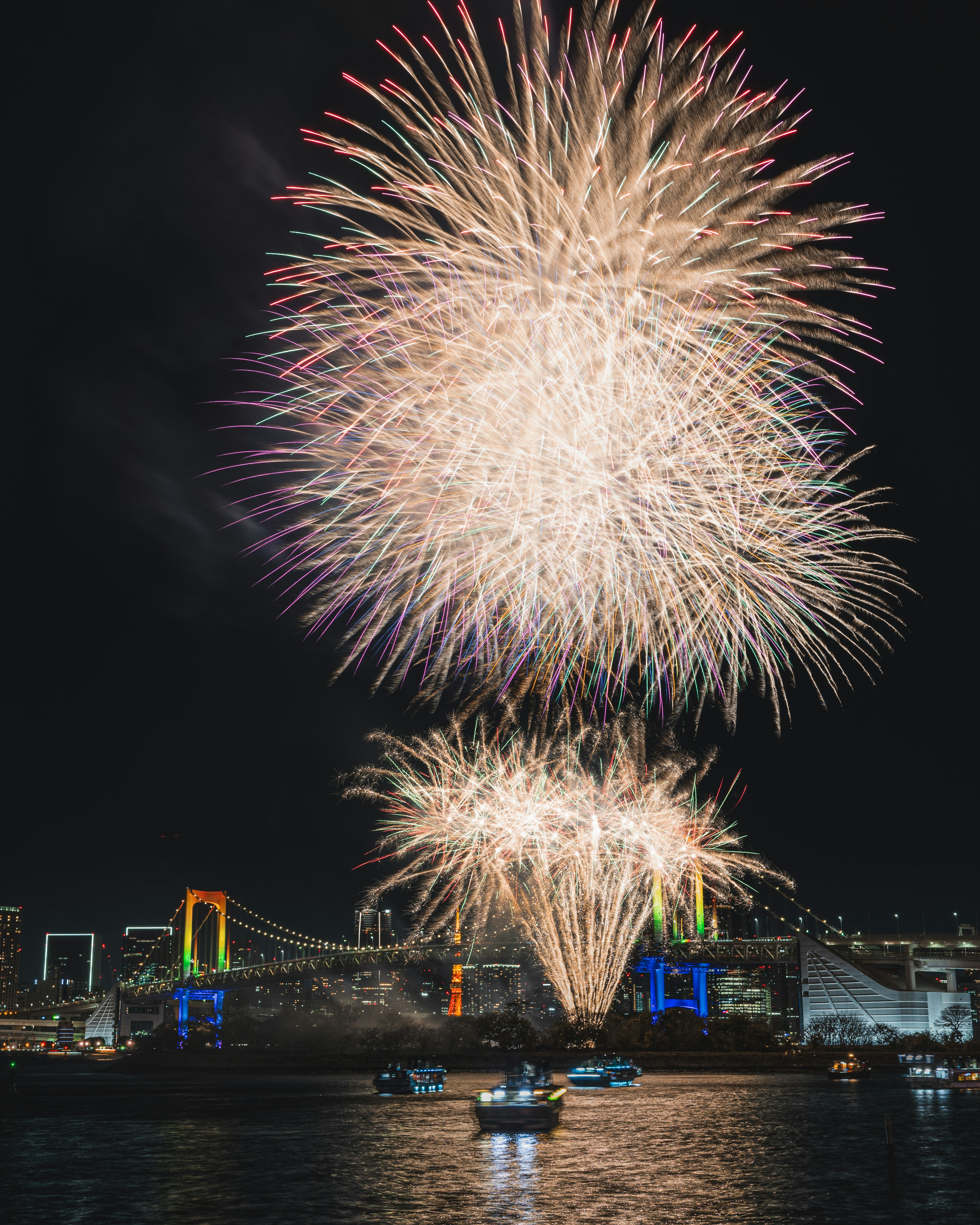 レインボーブリッジの背景に花火が打ち上がる夜景