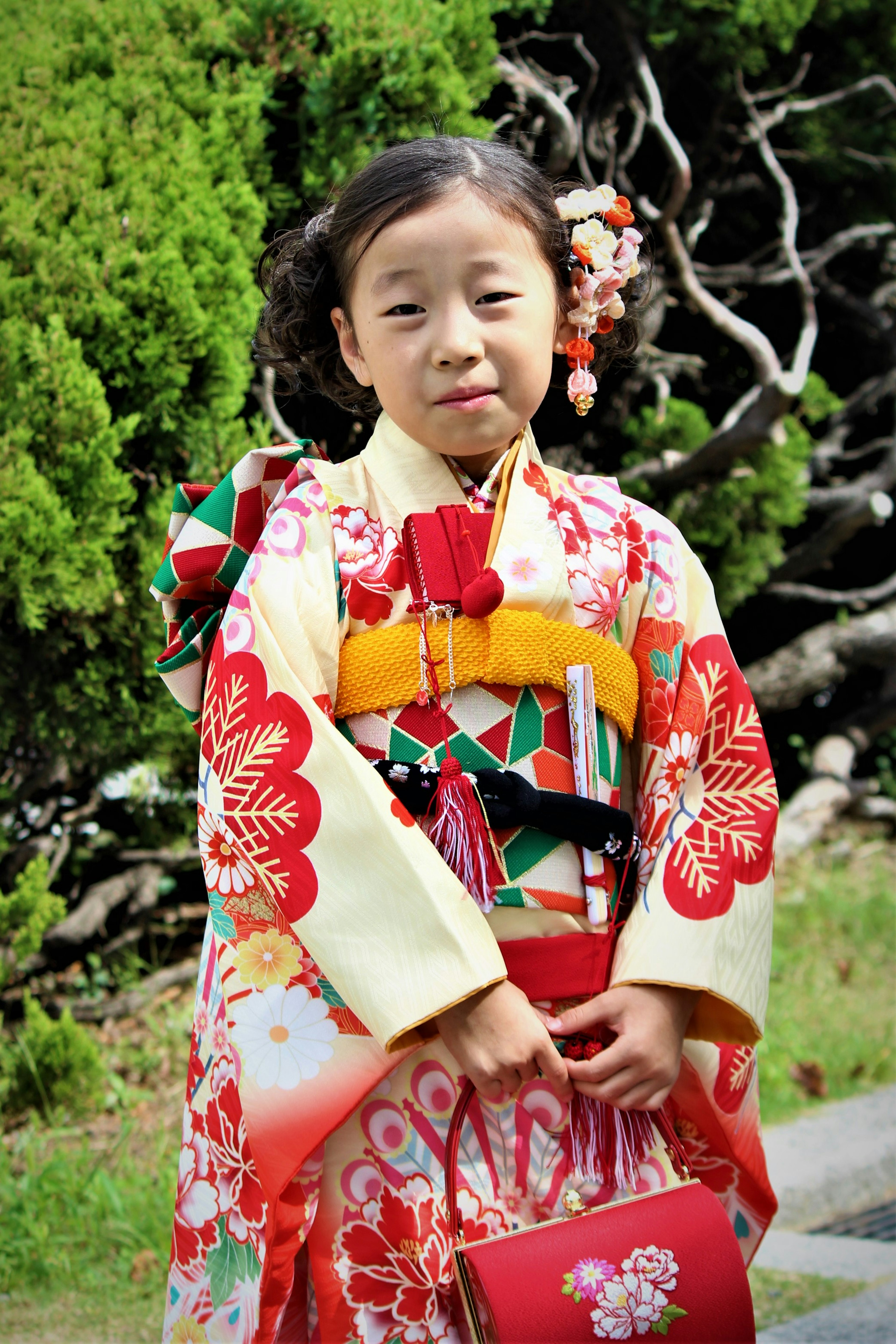 Seorang anak mengenakan kimono yang indah dengan pola bunga berwarna-warni dan aksesori bunga di rambutnya