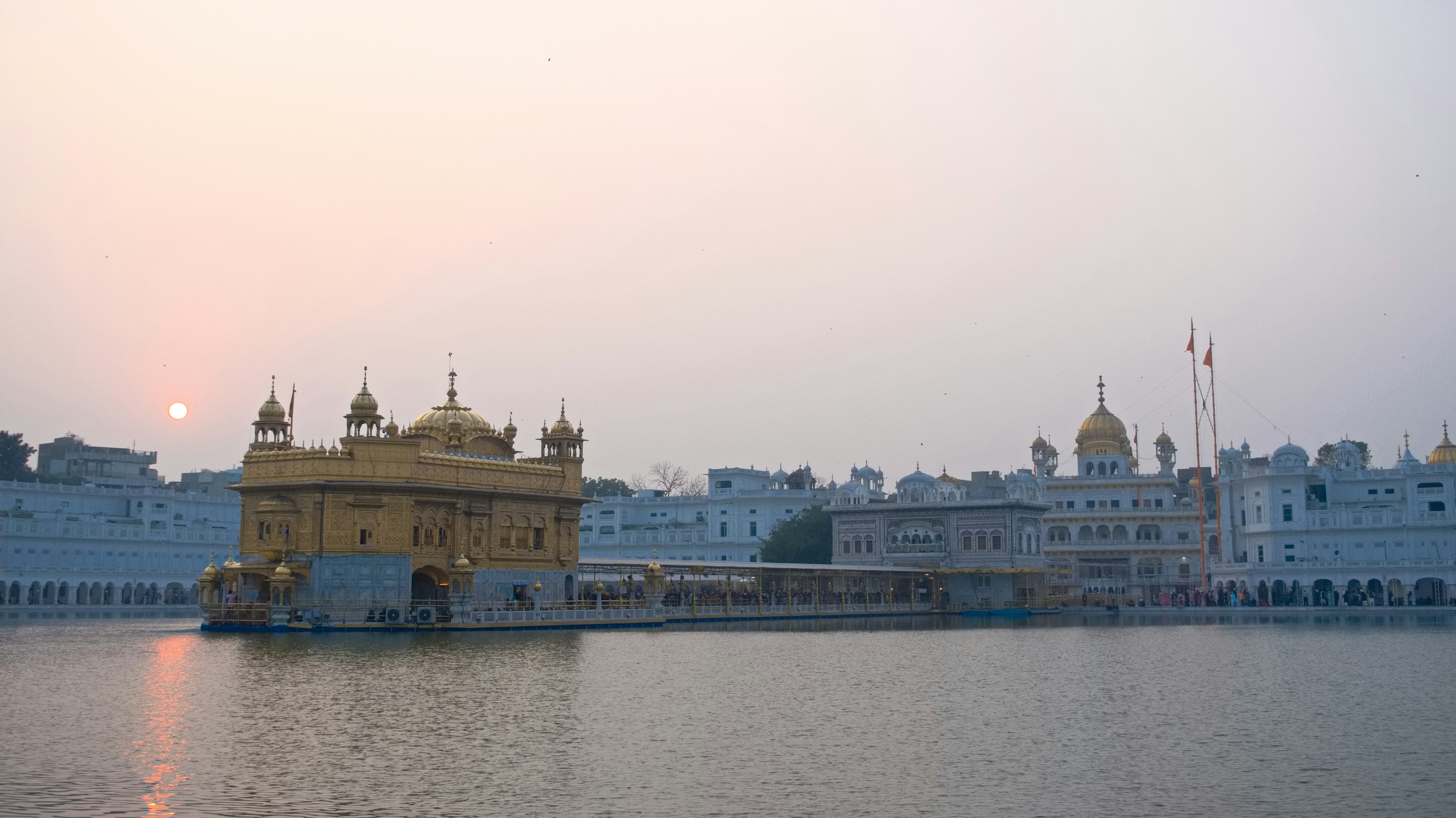 Golden temple with surrounding white buildings at sunset