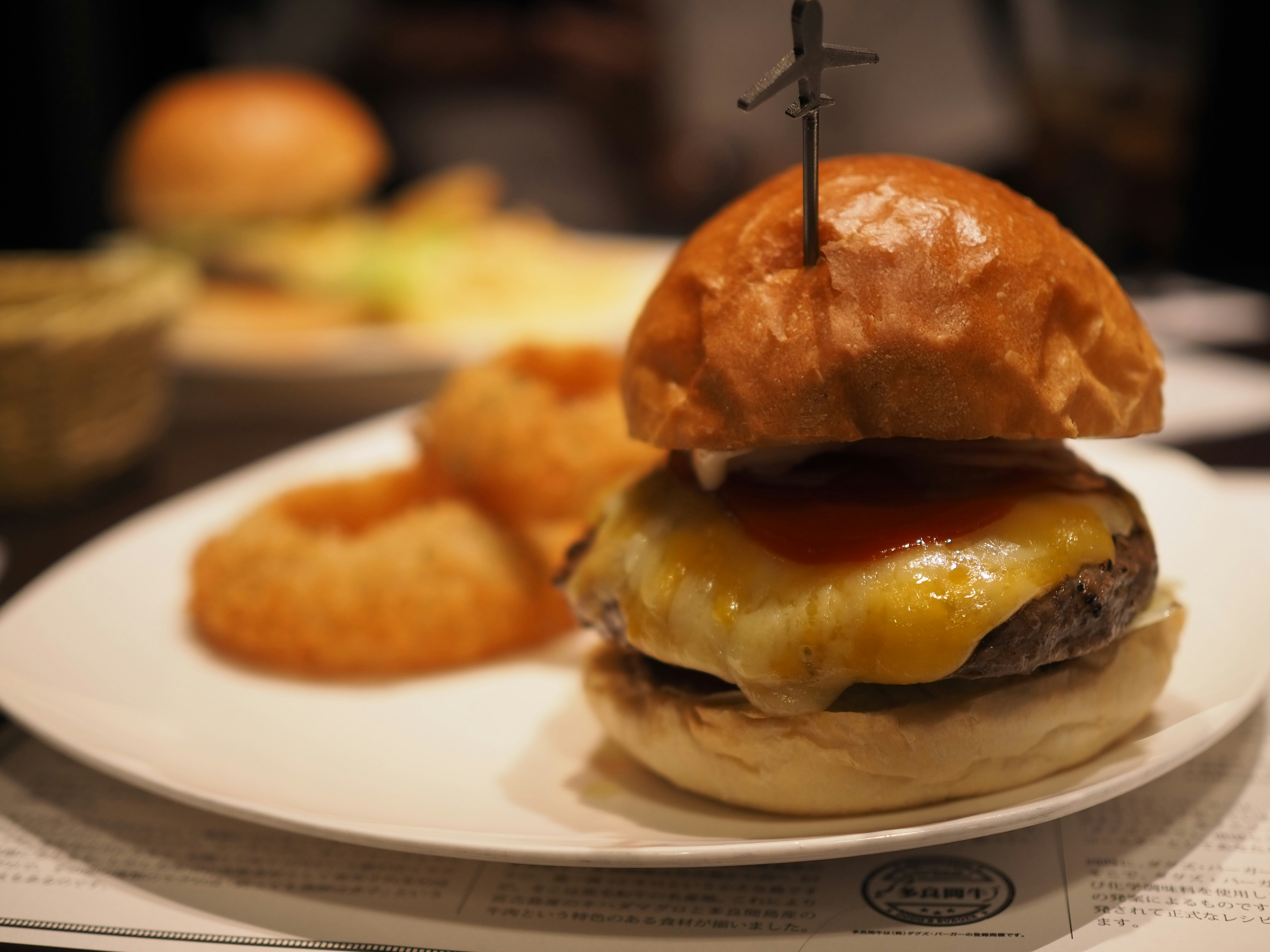 Hamburger lezat dengan keju dan saus tomat disajikan dengan cincin bawang