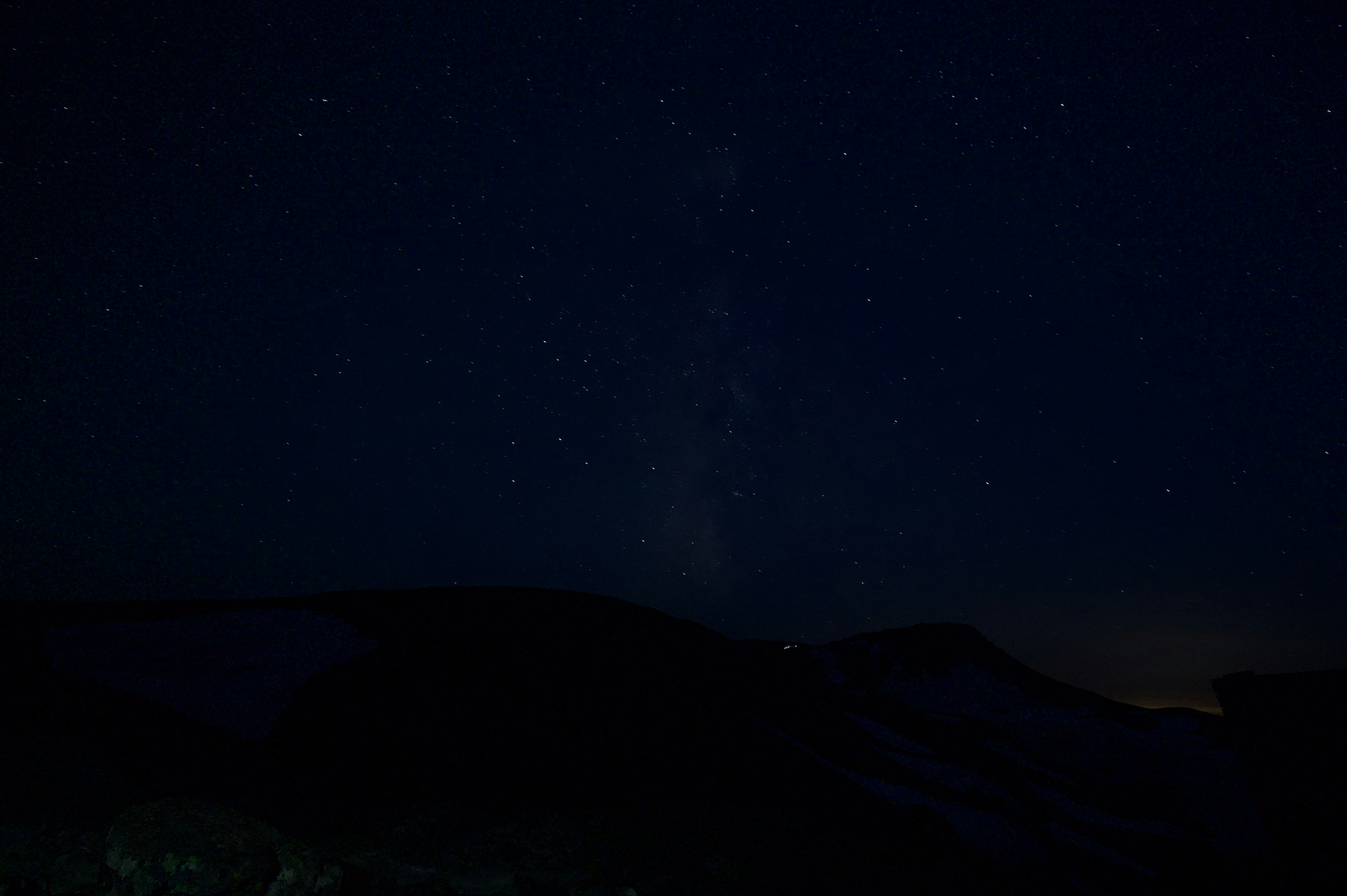 Cielo notturno pieno di stelle e silhouette di montagne