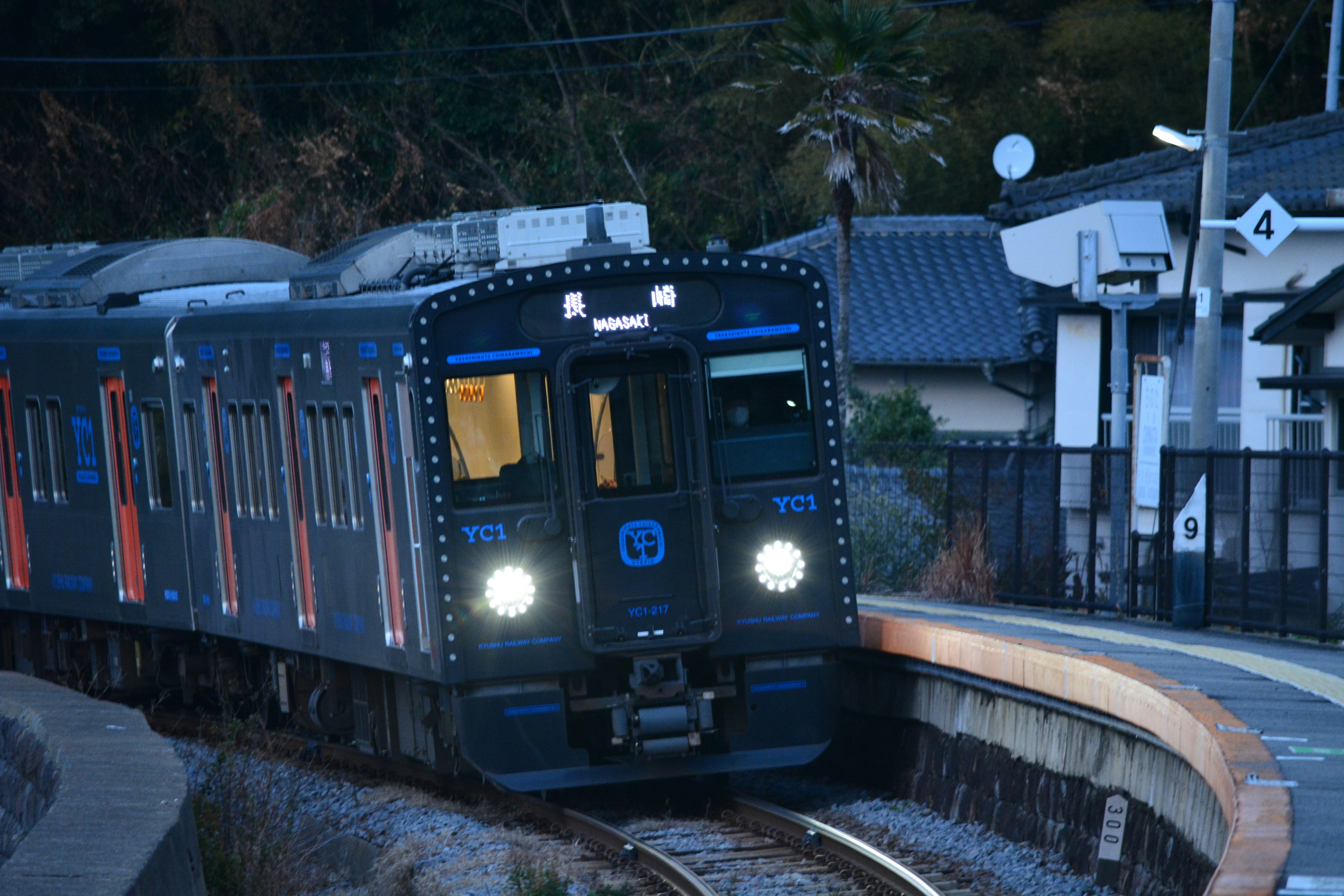 Train noir arrivant à une station au crépuscule