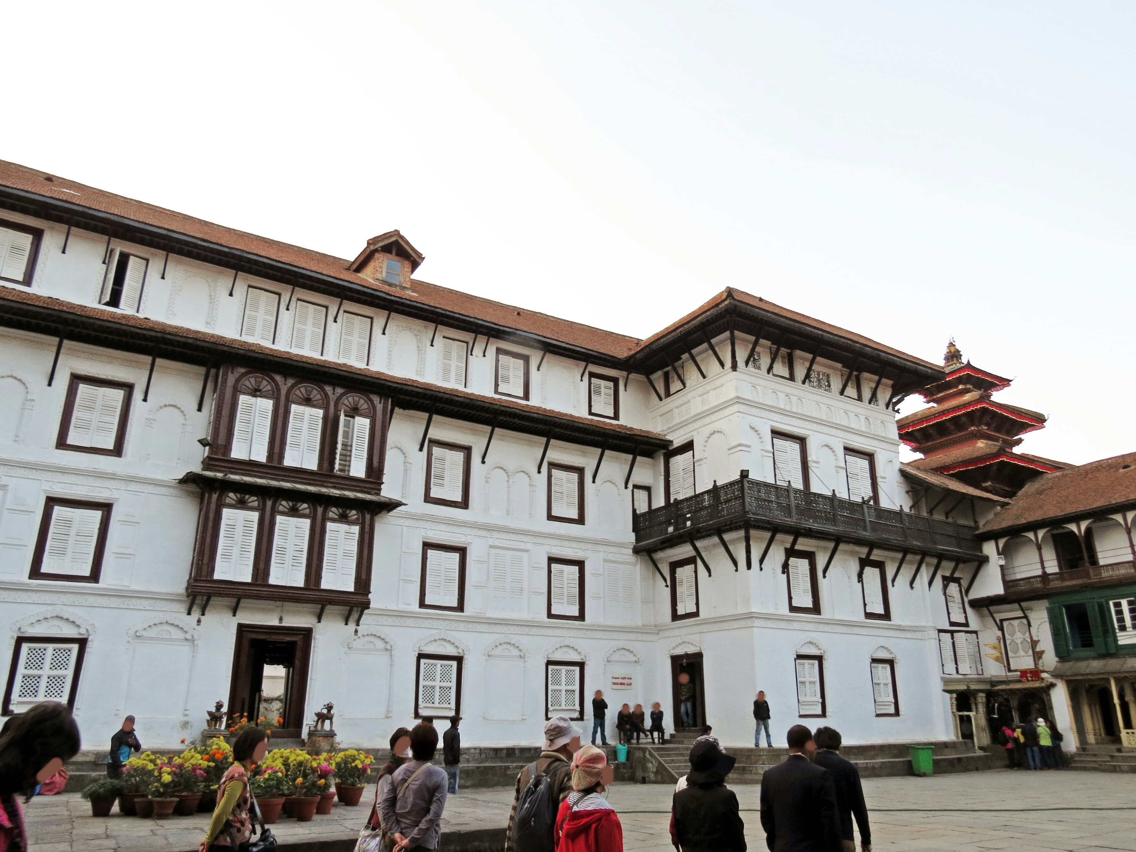 Vista exterior de un edificio blanco en la Plaza Durbar de Katmandú con visitantes