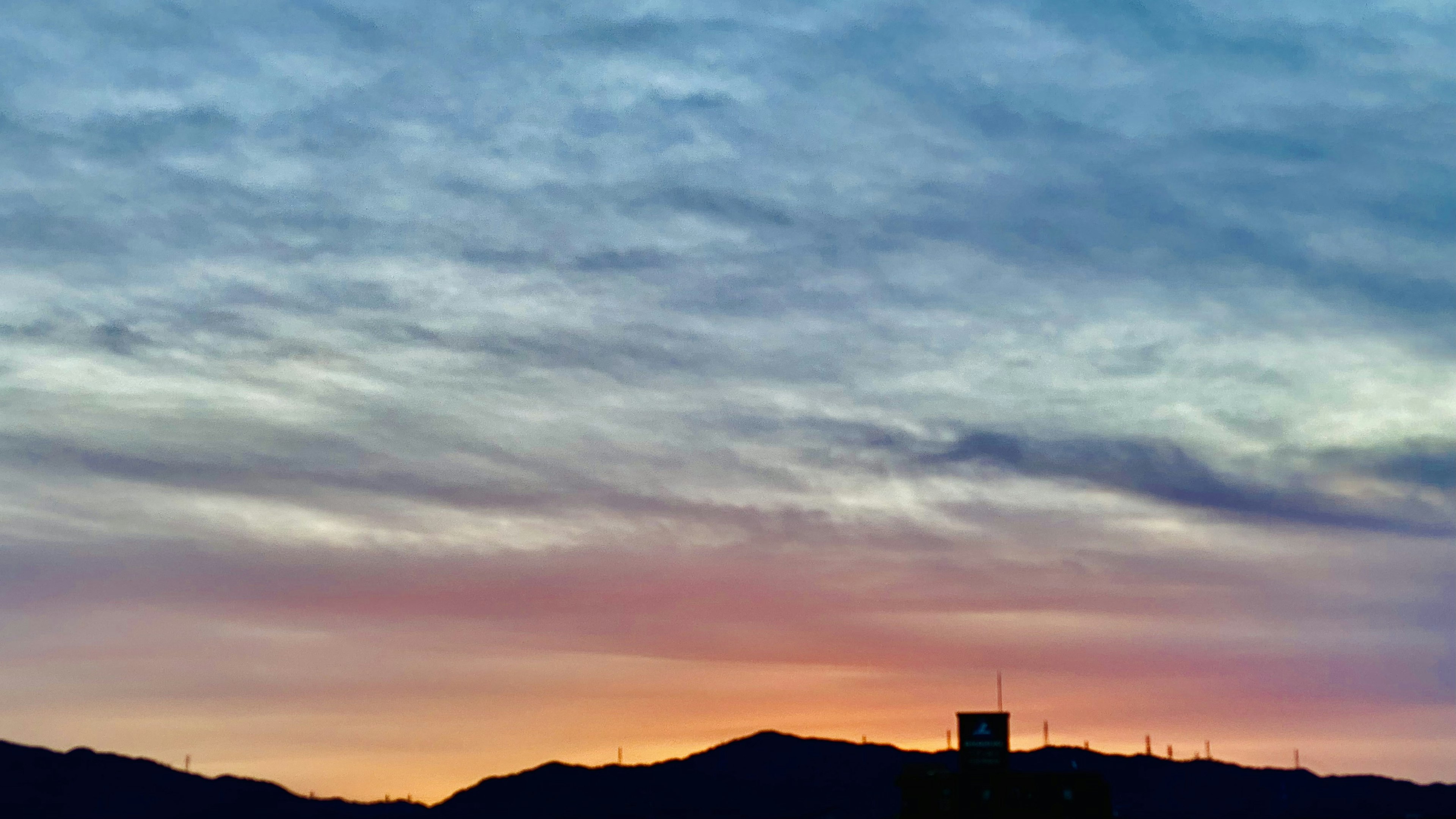 Beau ciel de coucher de soleil avec des montagnes en silhouette et une tour