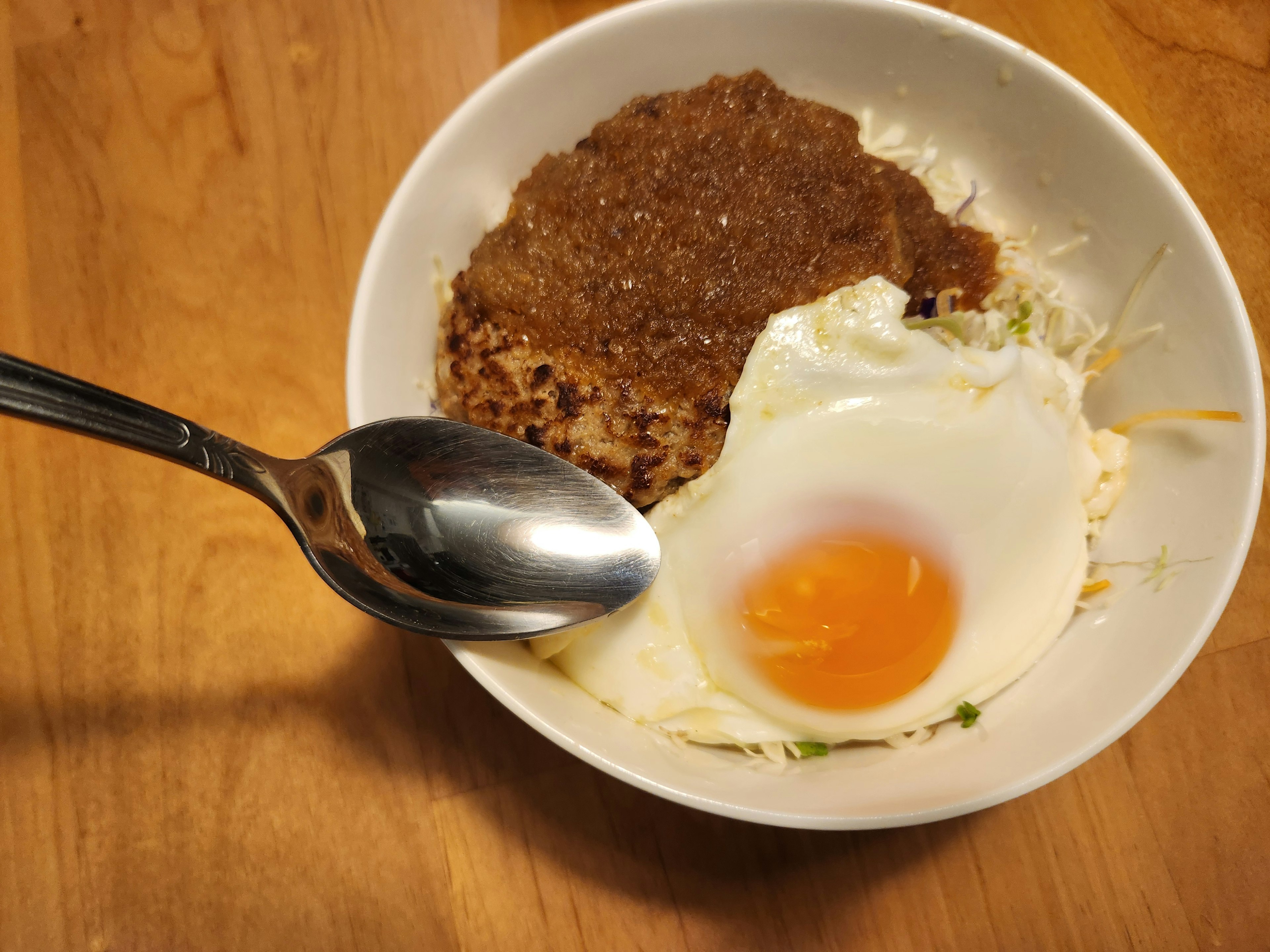 A bowl containing a fried egg and a portion of brown meatloaf