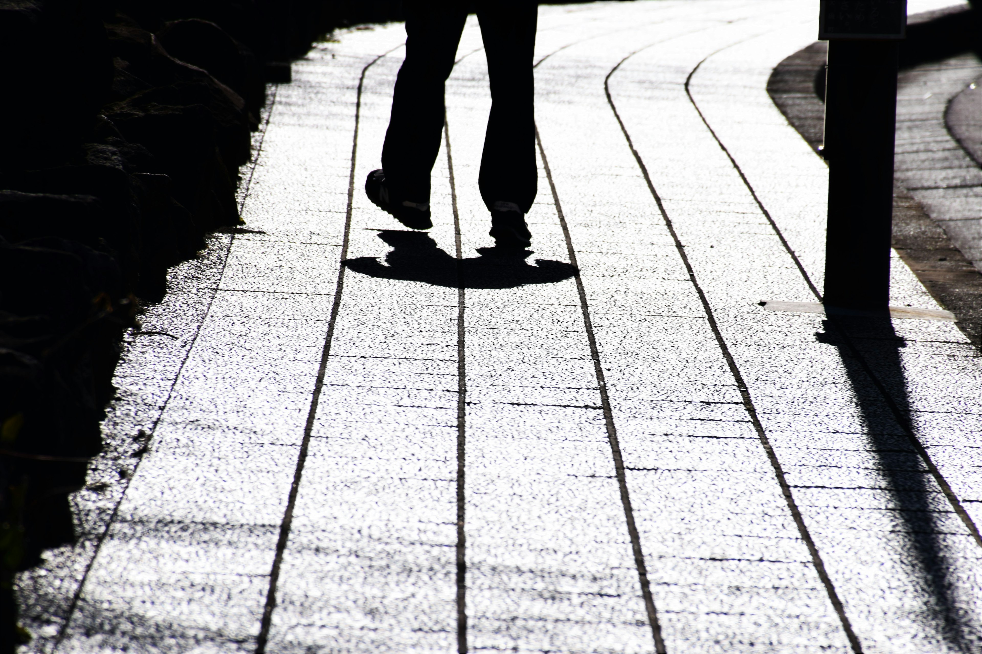 A person walking on a curved pathway with shadows