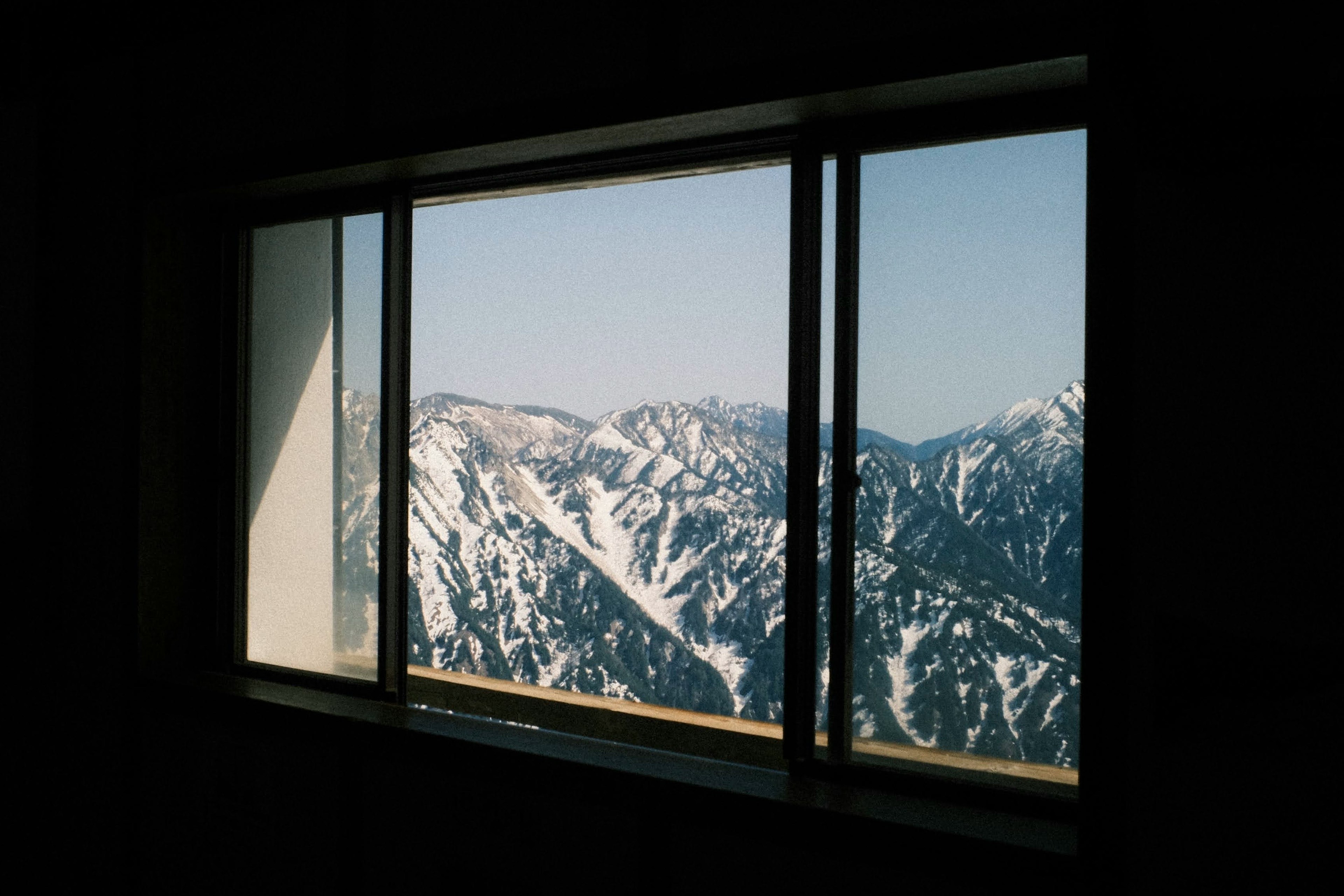 Blick auf schneebedeckte Berge durch ein Fenster