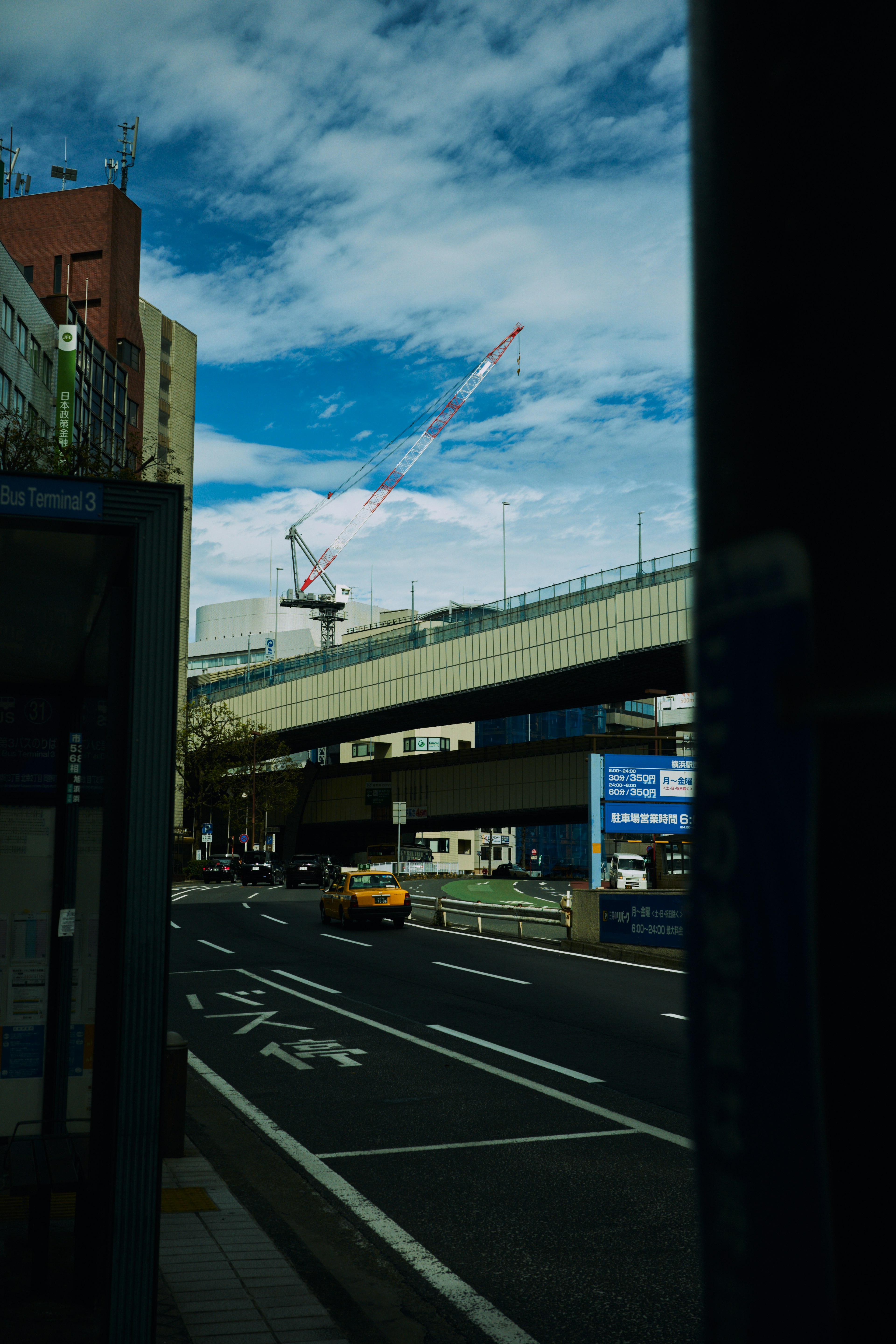 Vue d'une route surélevée sous un ciel bleu avec des feux de circulation et des grues de construction