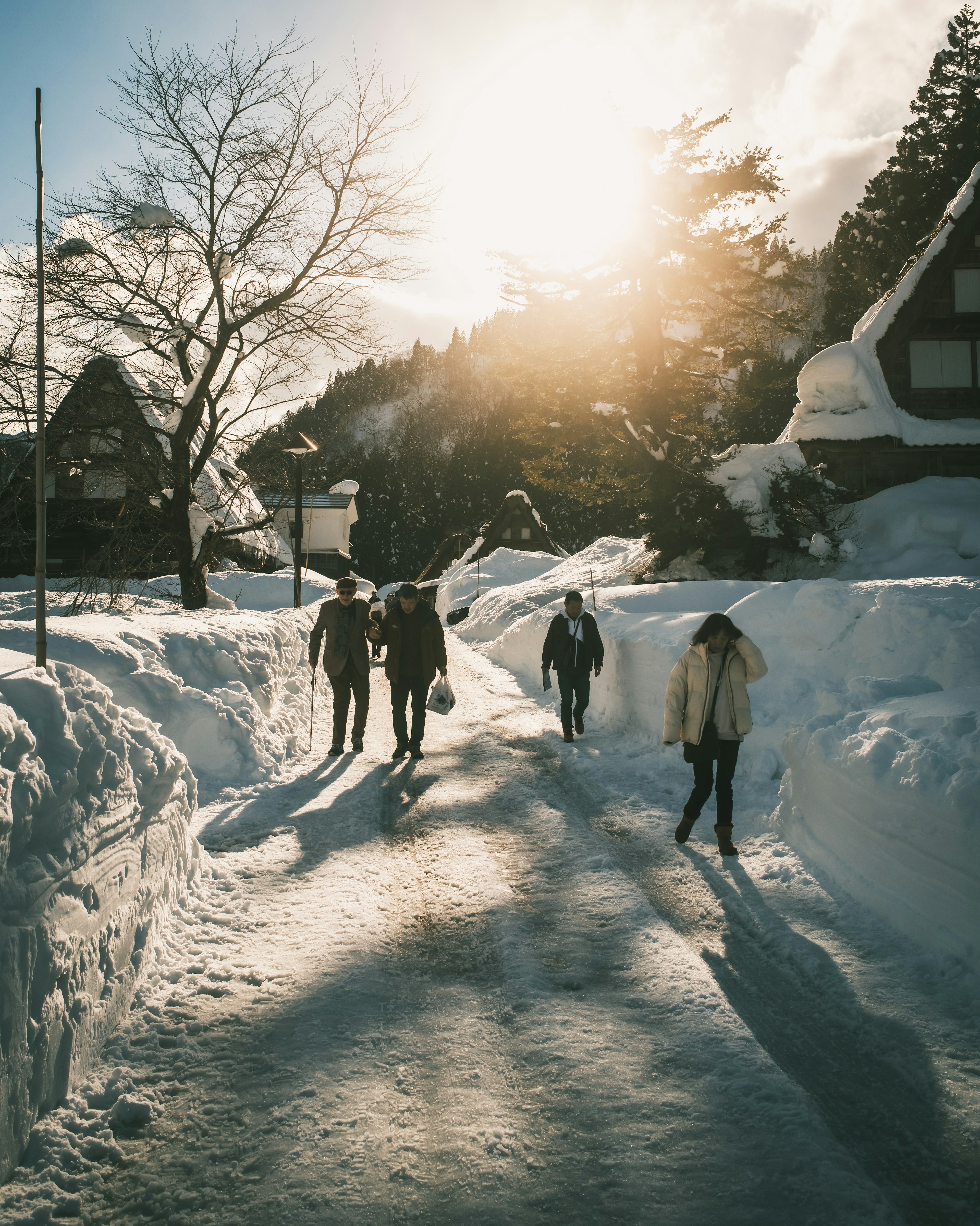 雪に覆われた道を歩く人々と夕日が輝く風景