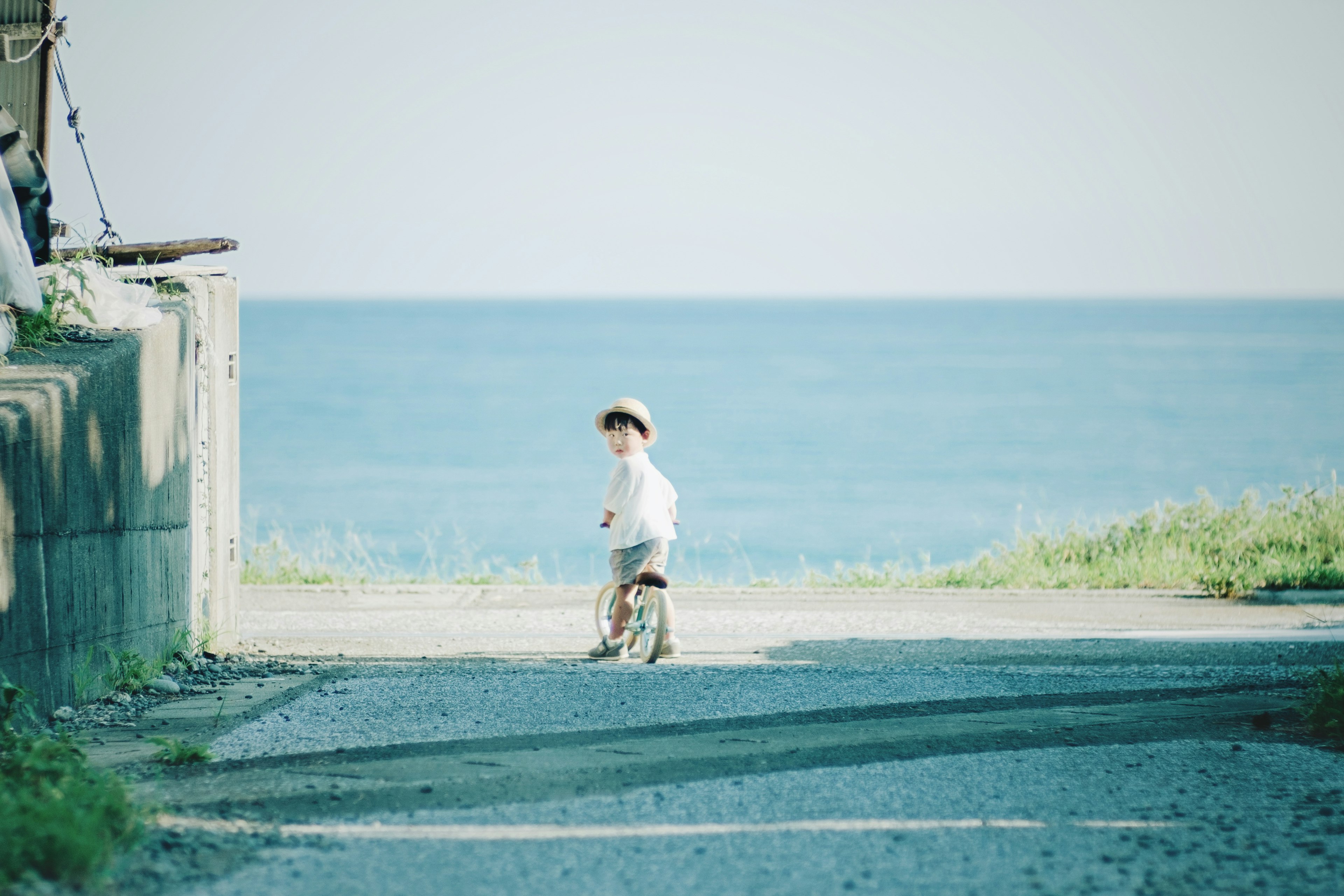 A child riding a bicycle near the sea