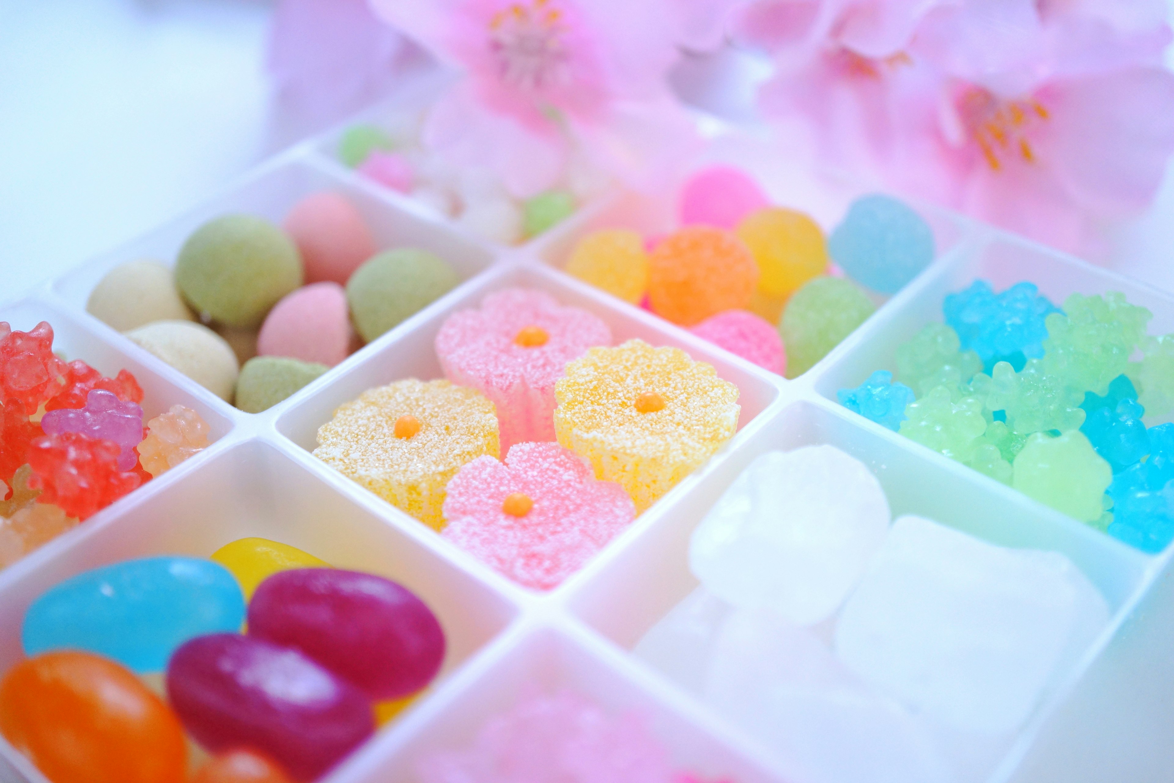 Dulces coloridos en una caja blanca con flores de cerezo