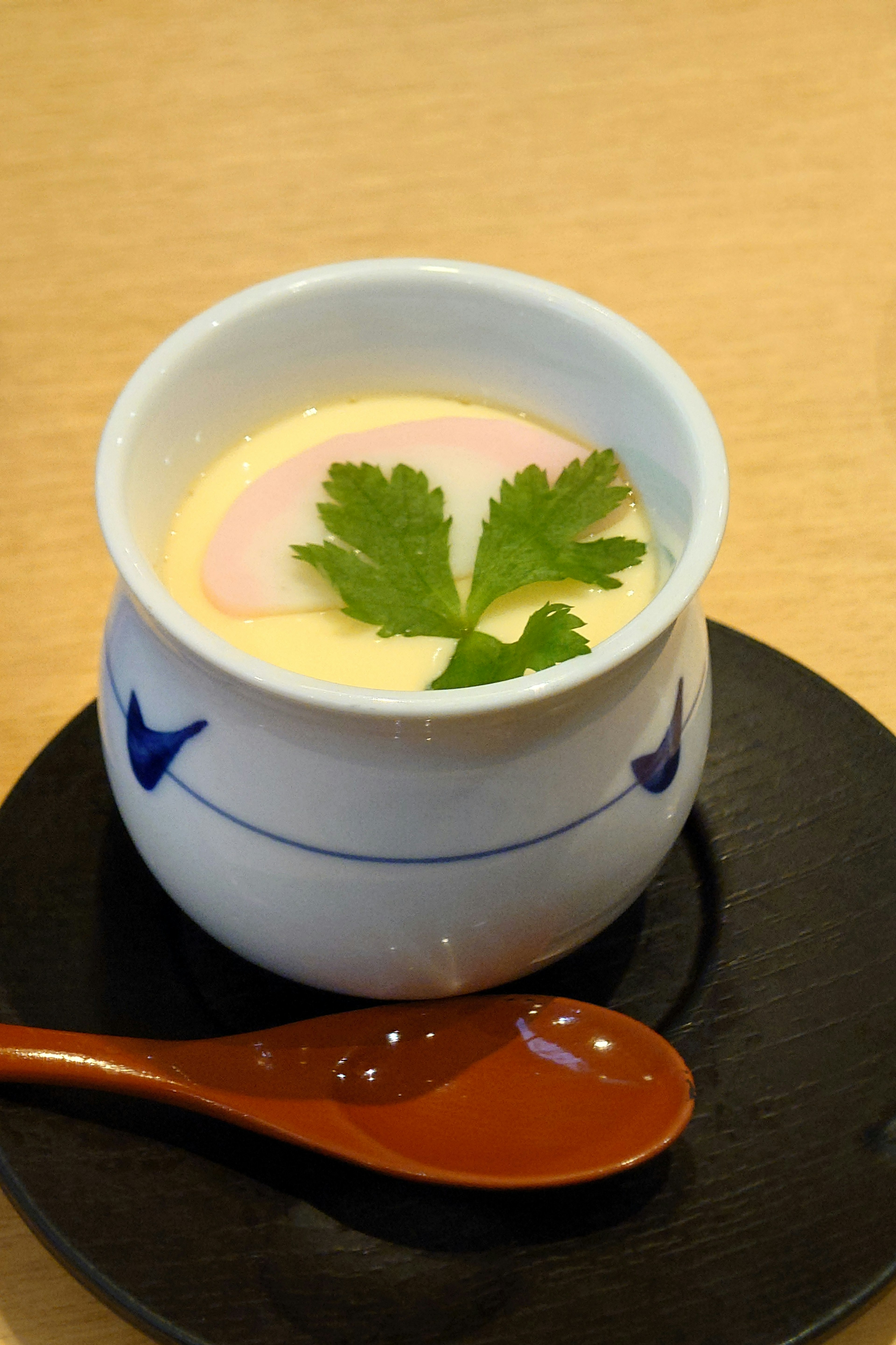 Chawanmushi en una taza blanca decorada con hojas de cilantro