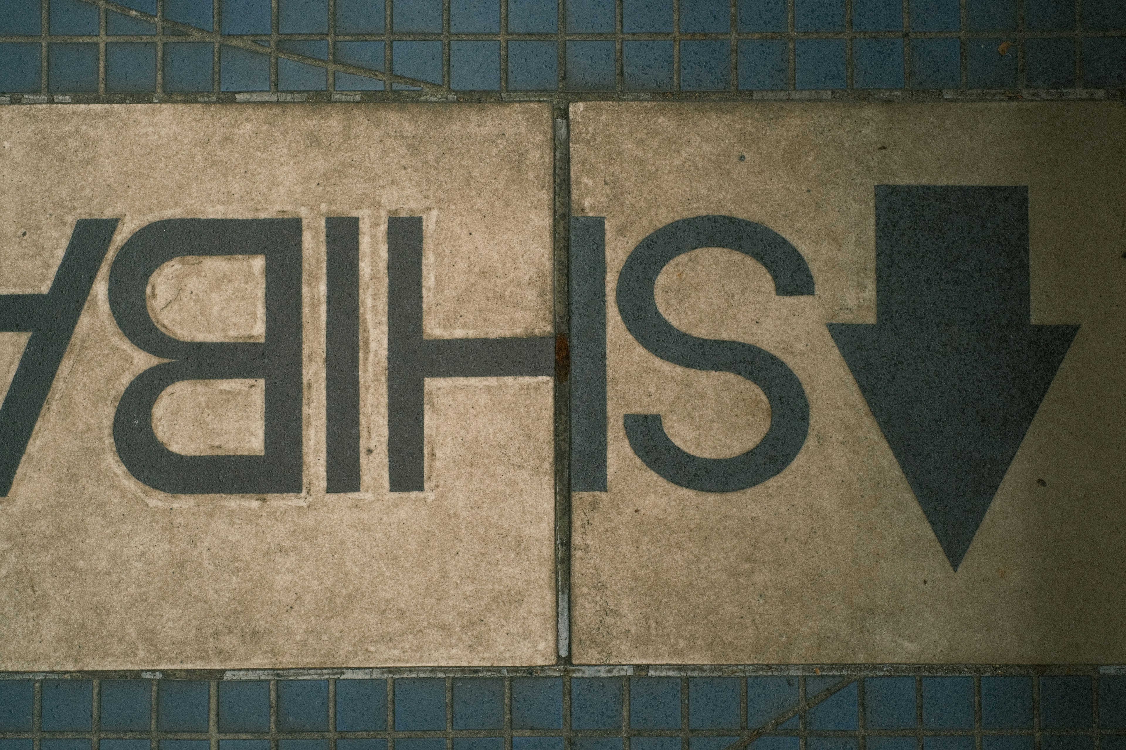 Inverted directional sign on tiled floor indicating down