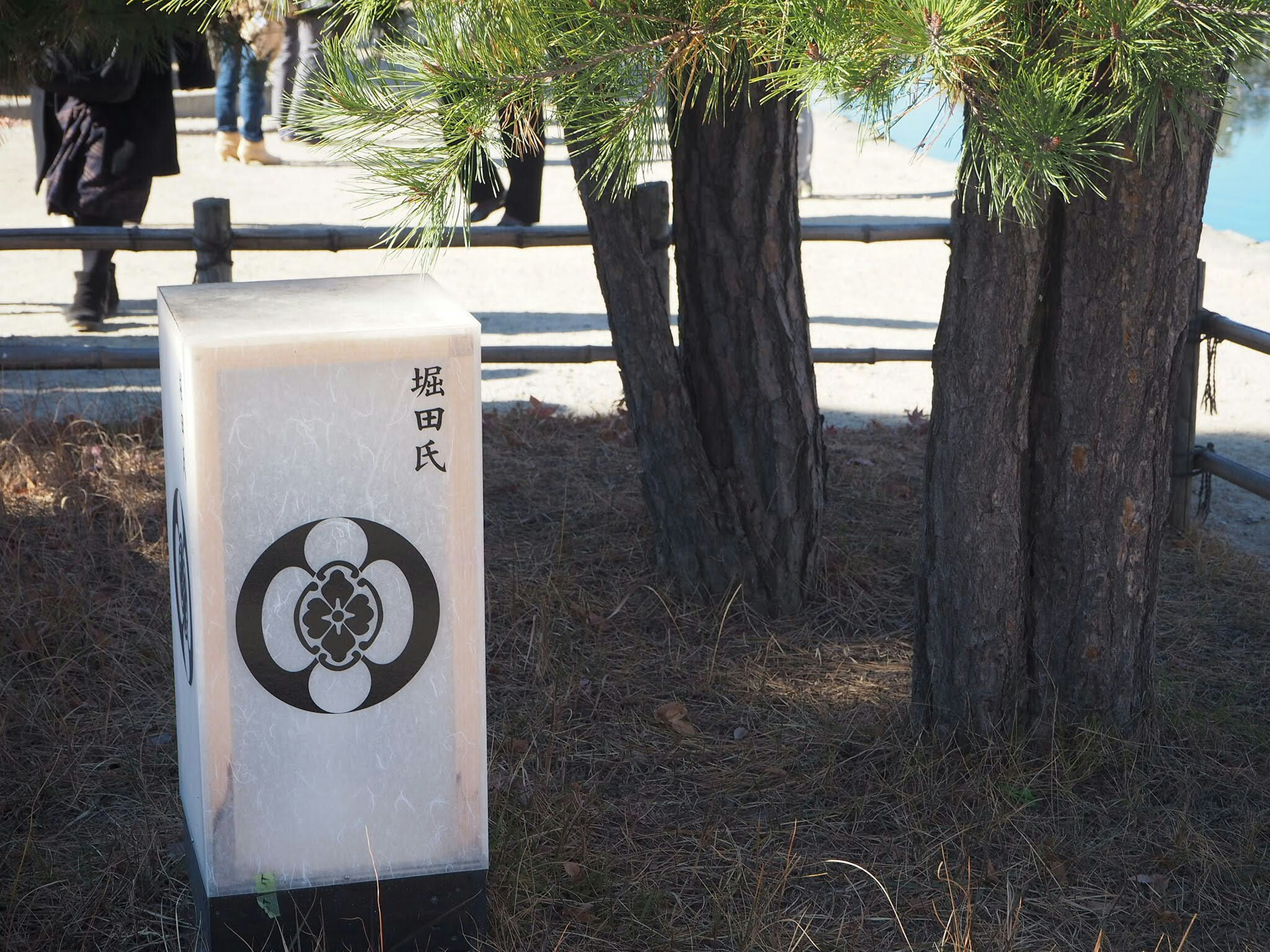 Stone marker with emblem beside pine trees