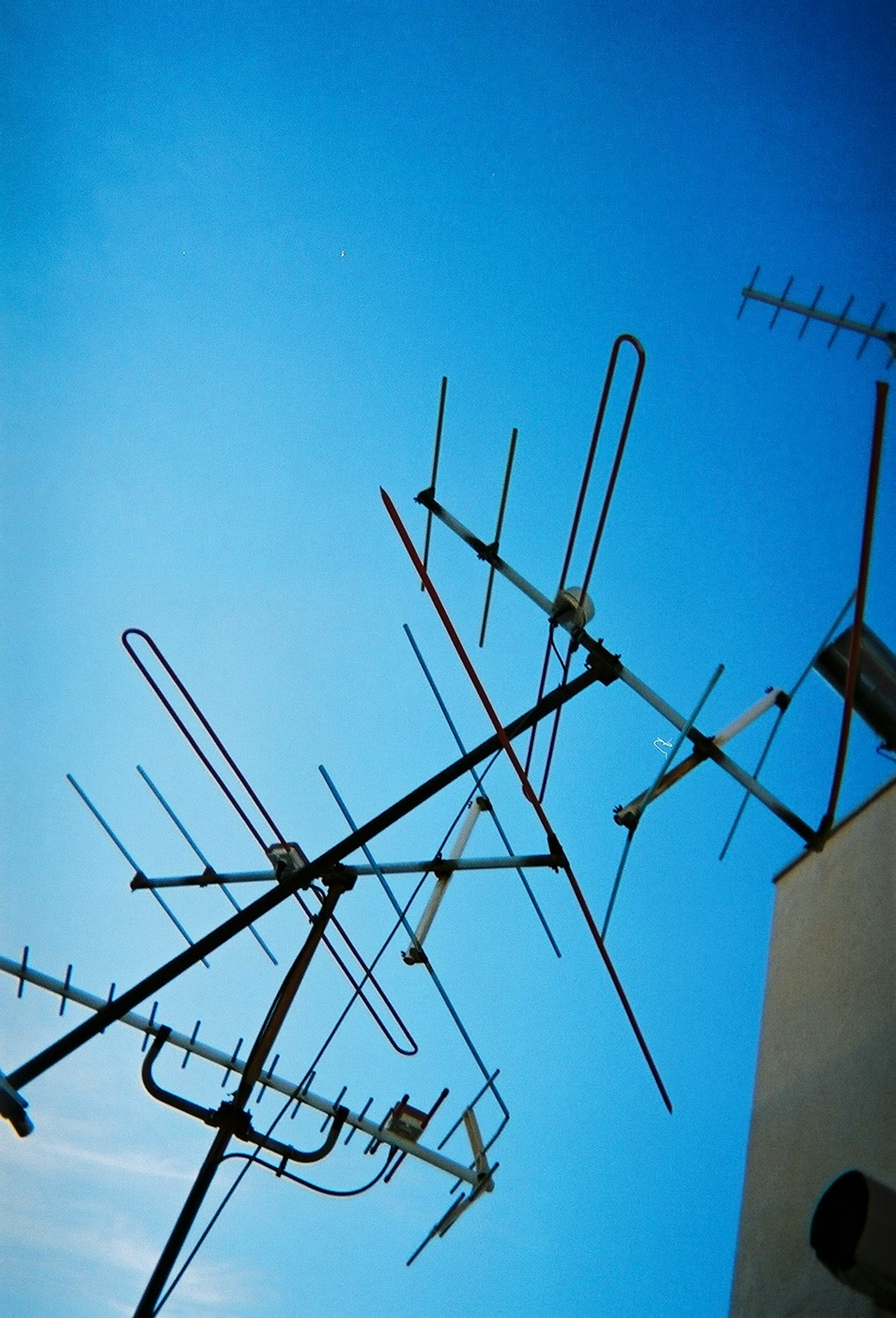 Multiple antennas on a building against a clear blue sky