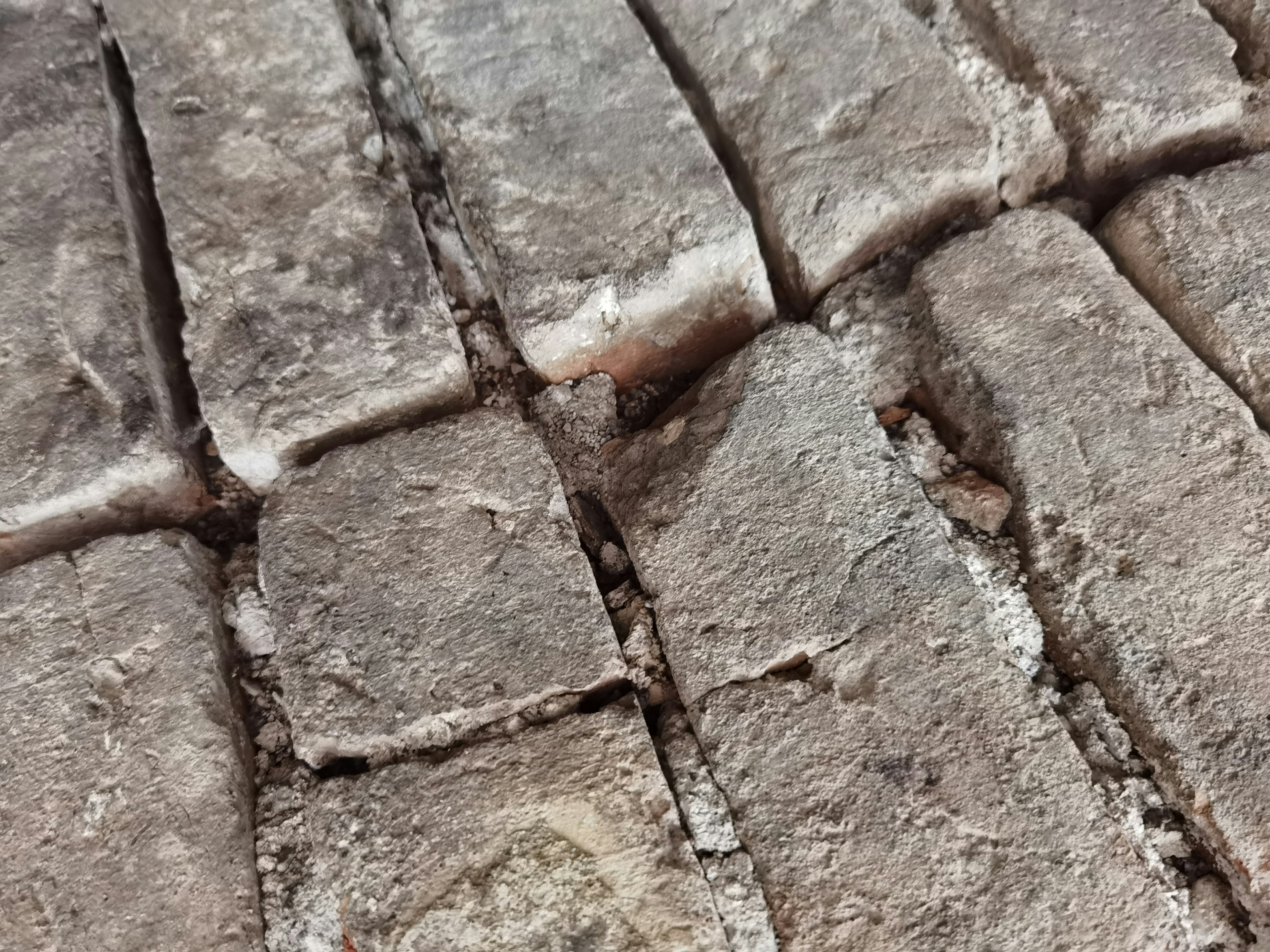 Close-up of an old cobblestone surface showing cracks and uneven texture