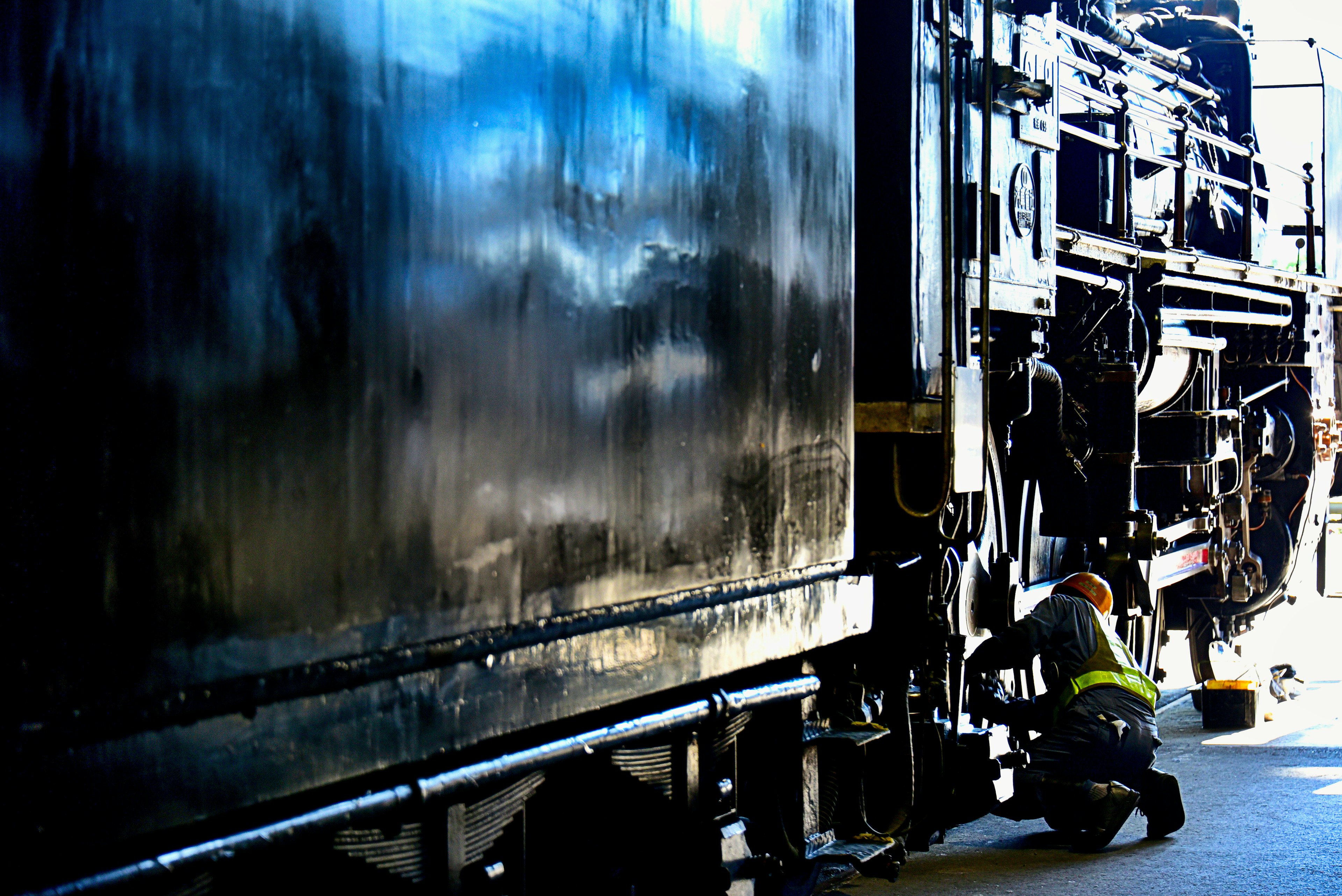 Techniker arbeitet in der Nähe einer schwarzen Dampflokomotive