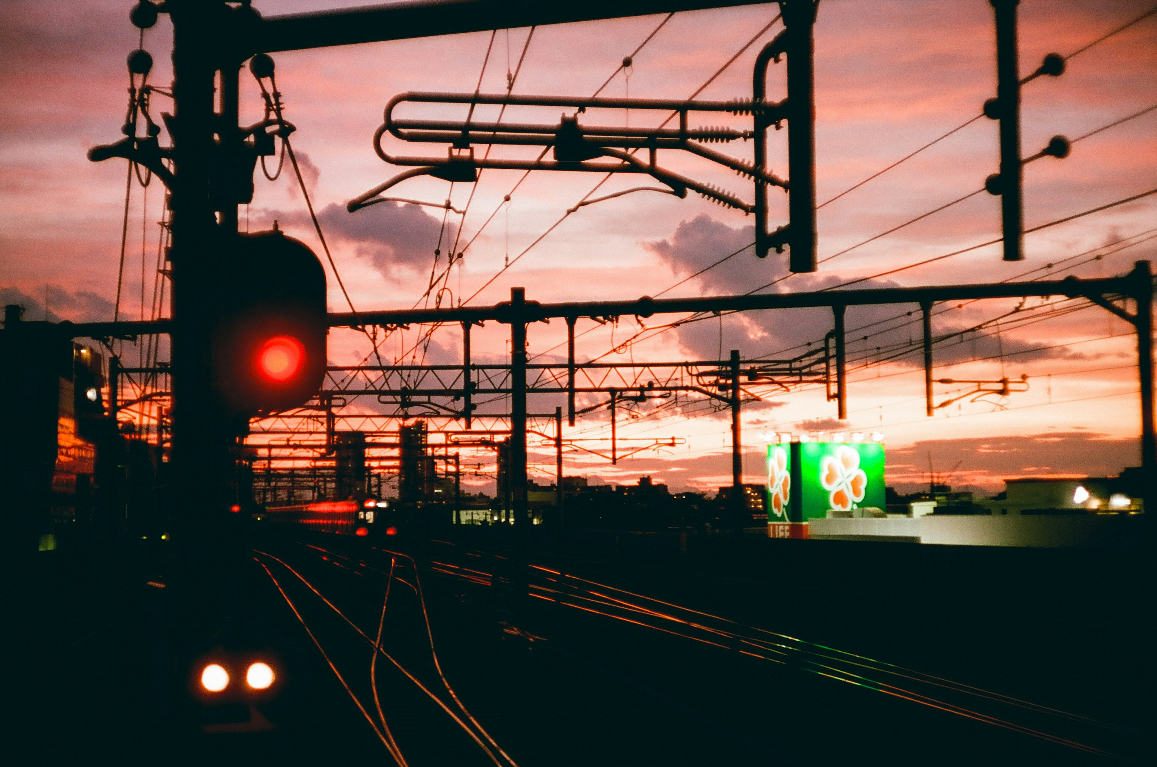 Scène ferroviaire au coucher du soleil avec feux de signalisation et fils aériens