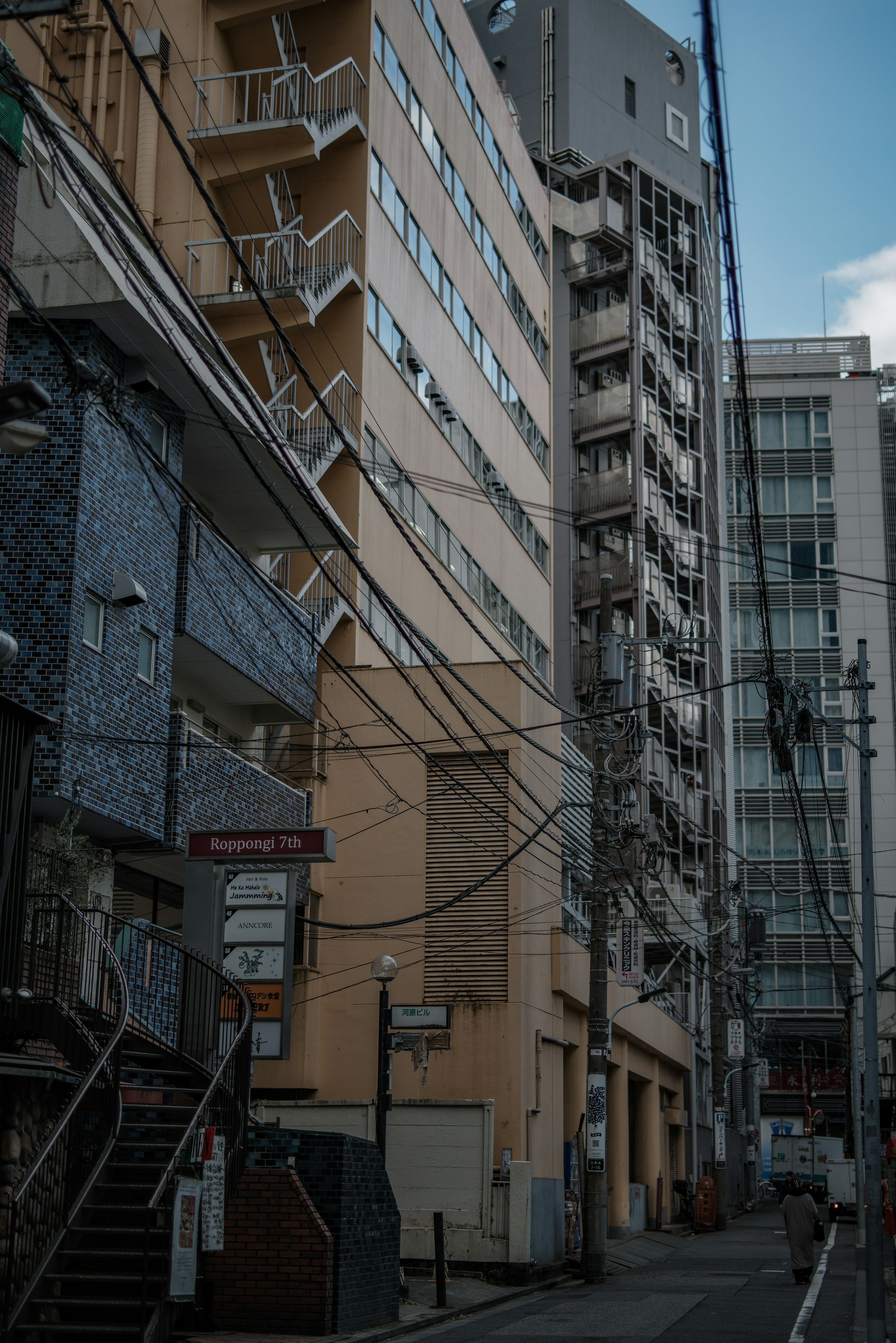 狭い通りに面した高層ビルと住宅が立ち並ぶ風景