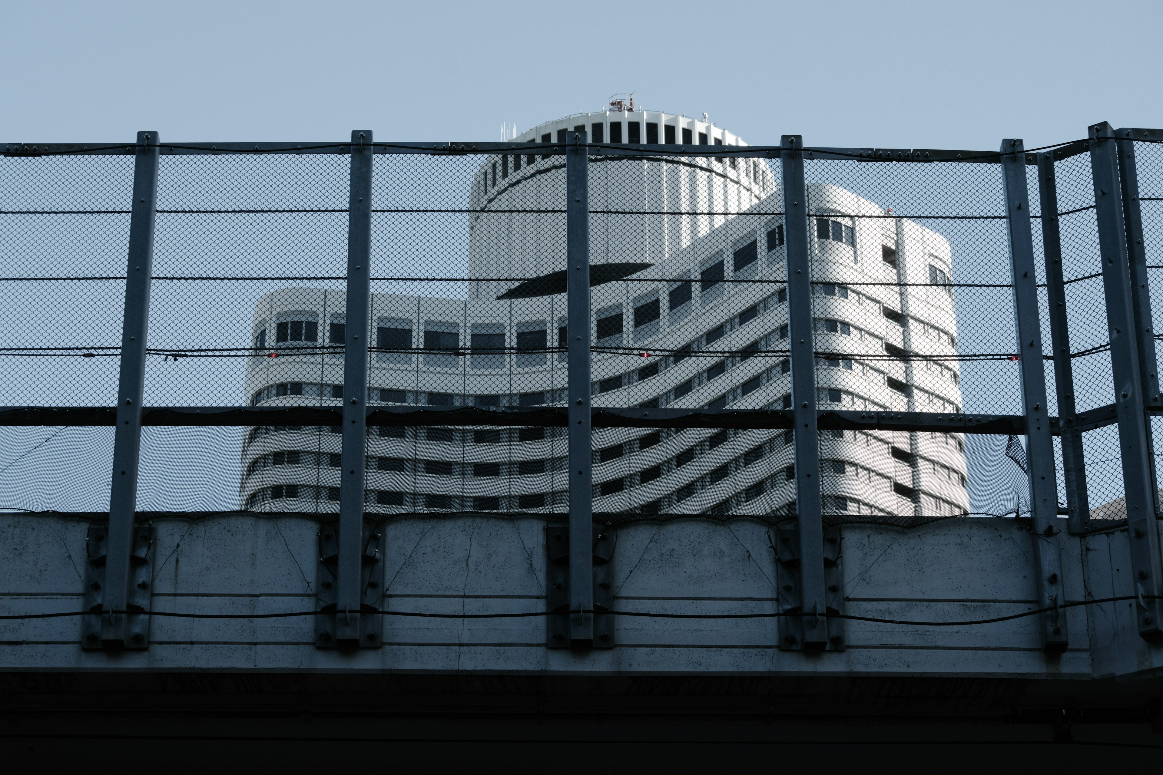 Silhouette of a skyscraper visible behind a metal fence