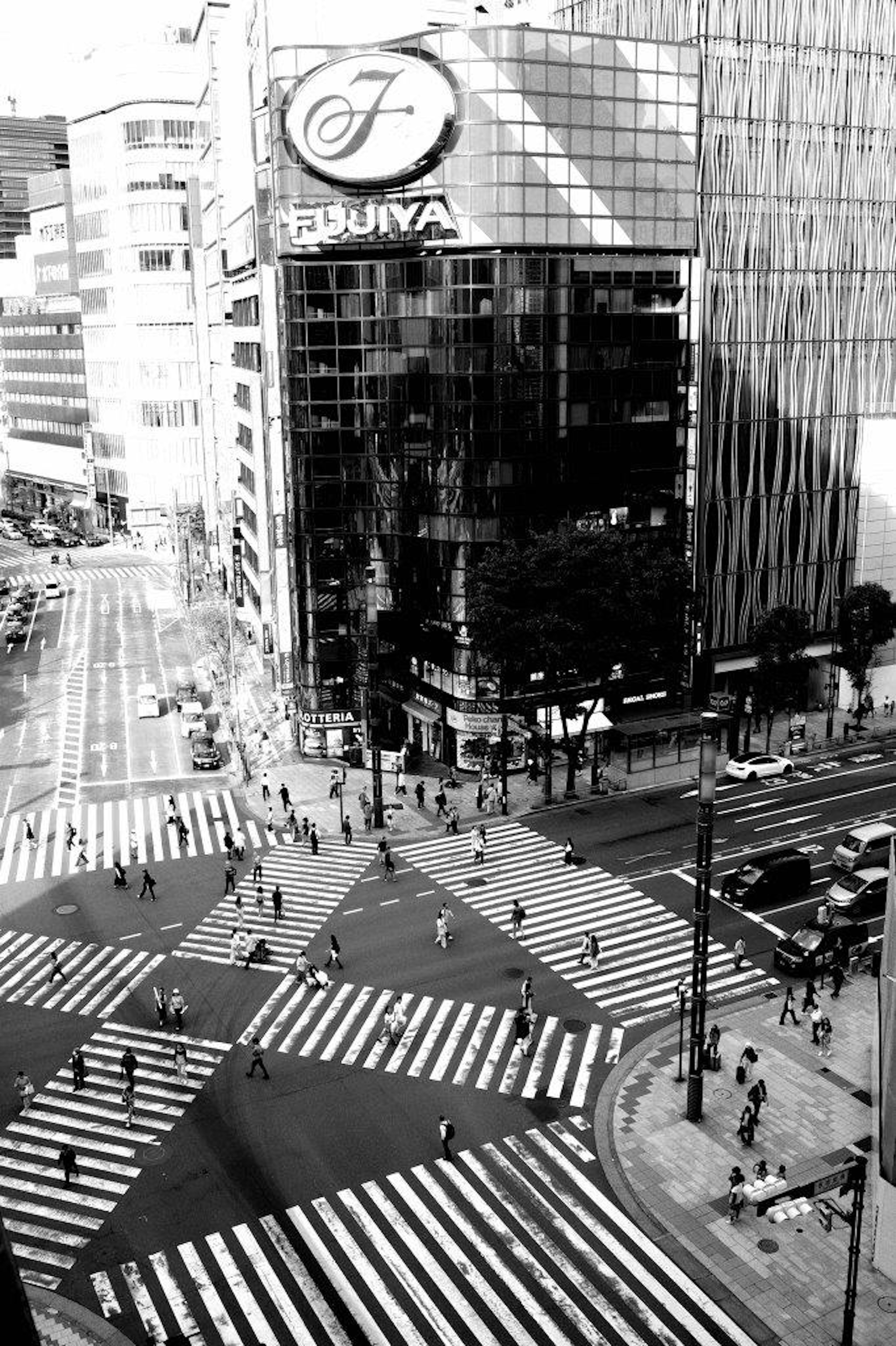 Black and white photo of Shibuya crossing showing many pedestrians on crosswalks