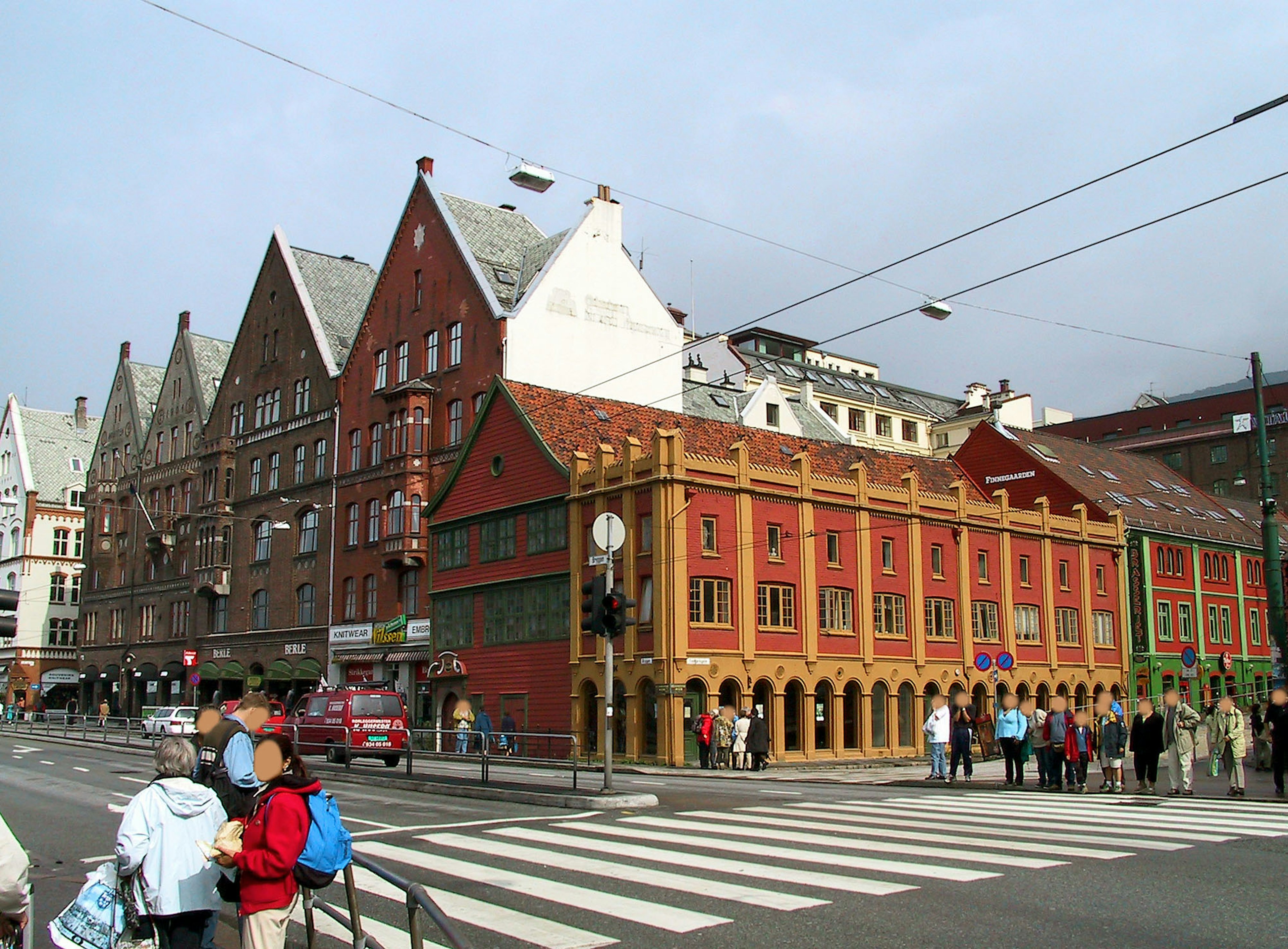 Colorful buildings in the Bryggen area with people crossing the street