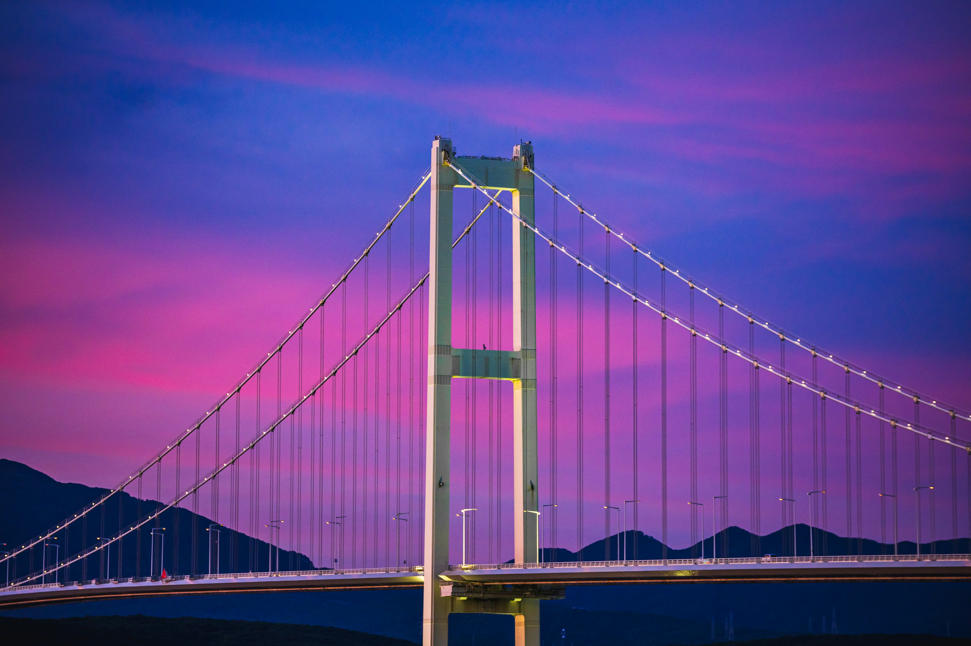 Hängende Brücke vor einem lebhaften lila Himmel beleuchtet