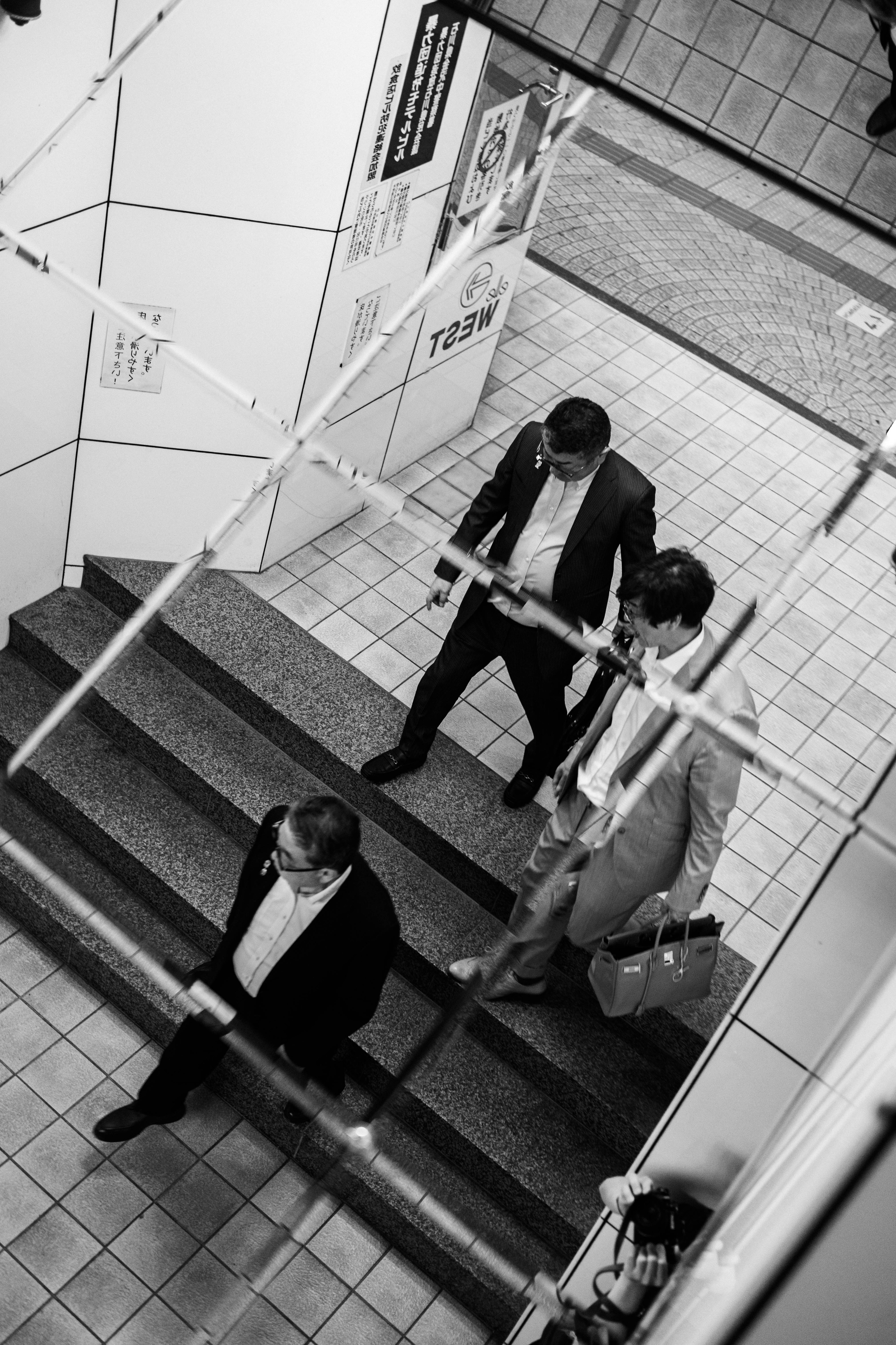 Trois hommes d'affaires descendant un escalier en noir et blanc