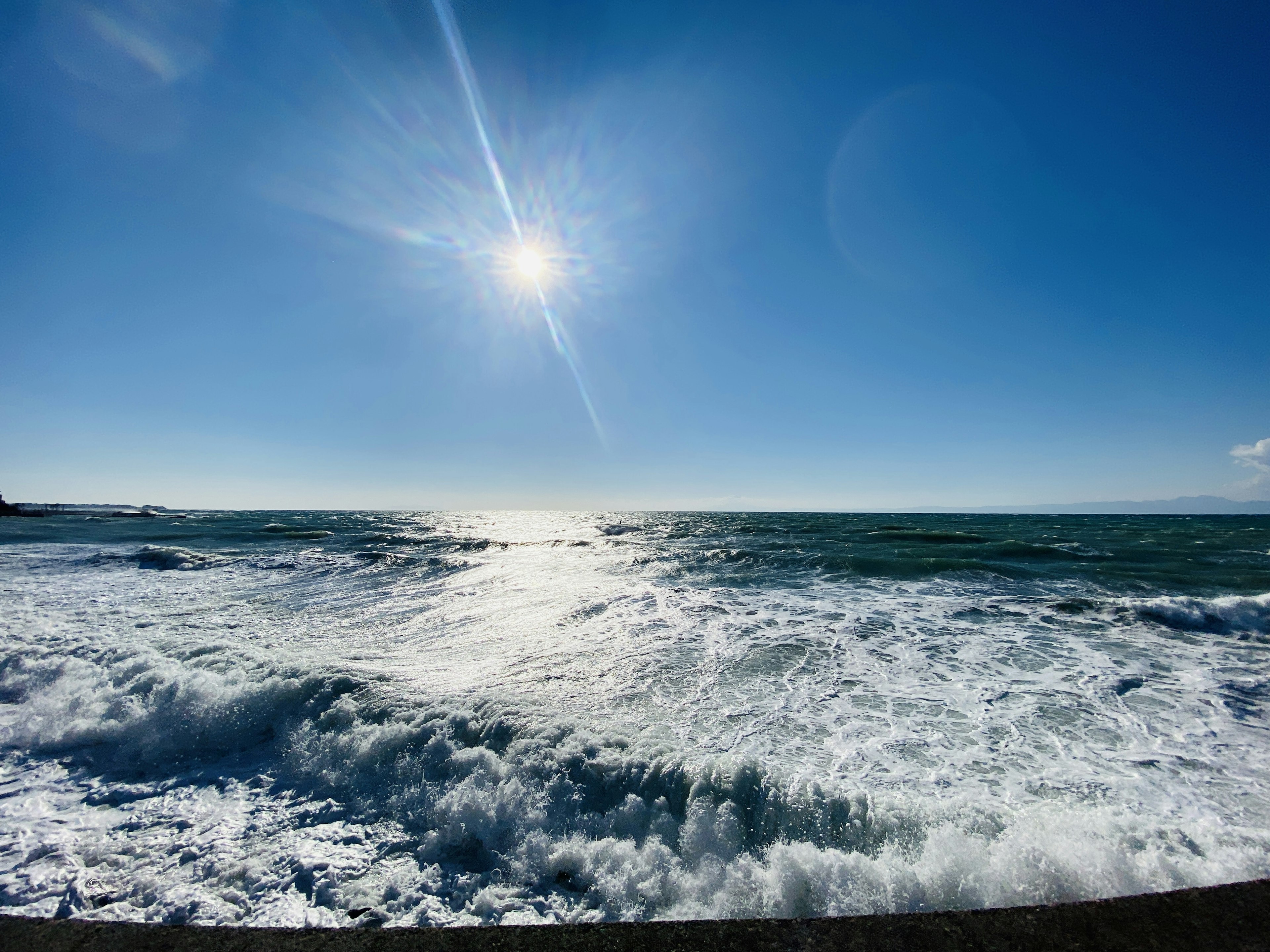 Paysage marin avec des vagues s'écrasant sous un soleil brillant et un ciel bleu clair