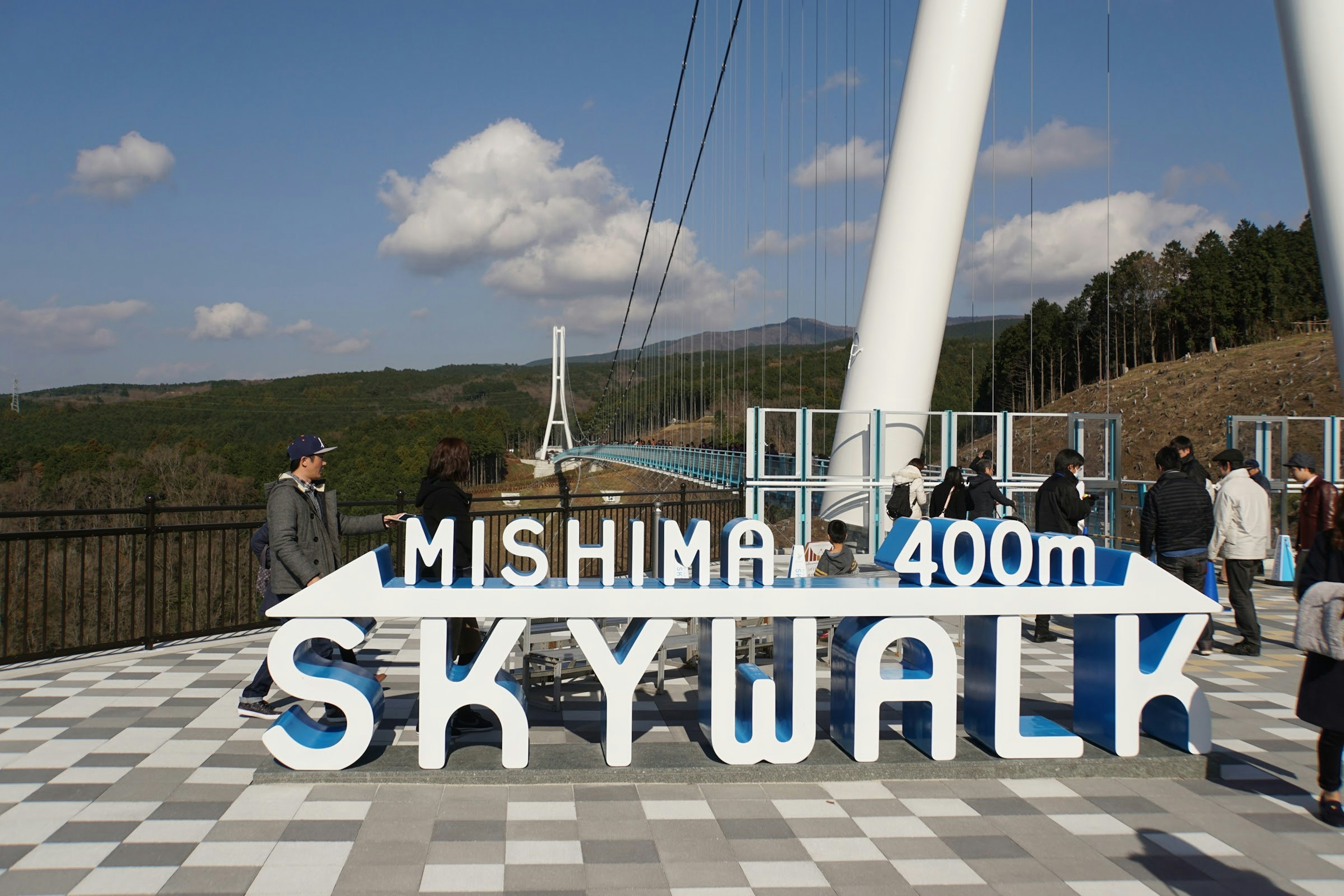 Visitors at the entrance of Mishima 400m Skywalk with a blue sign