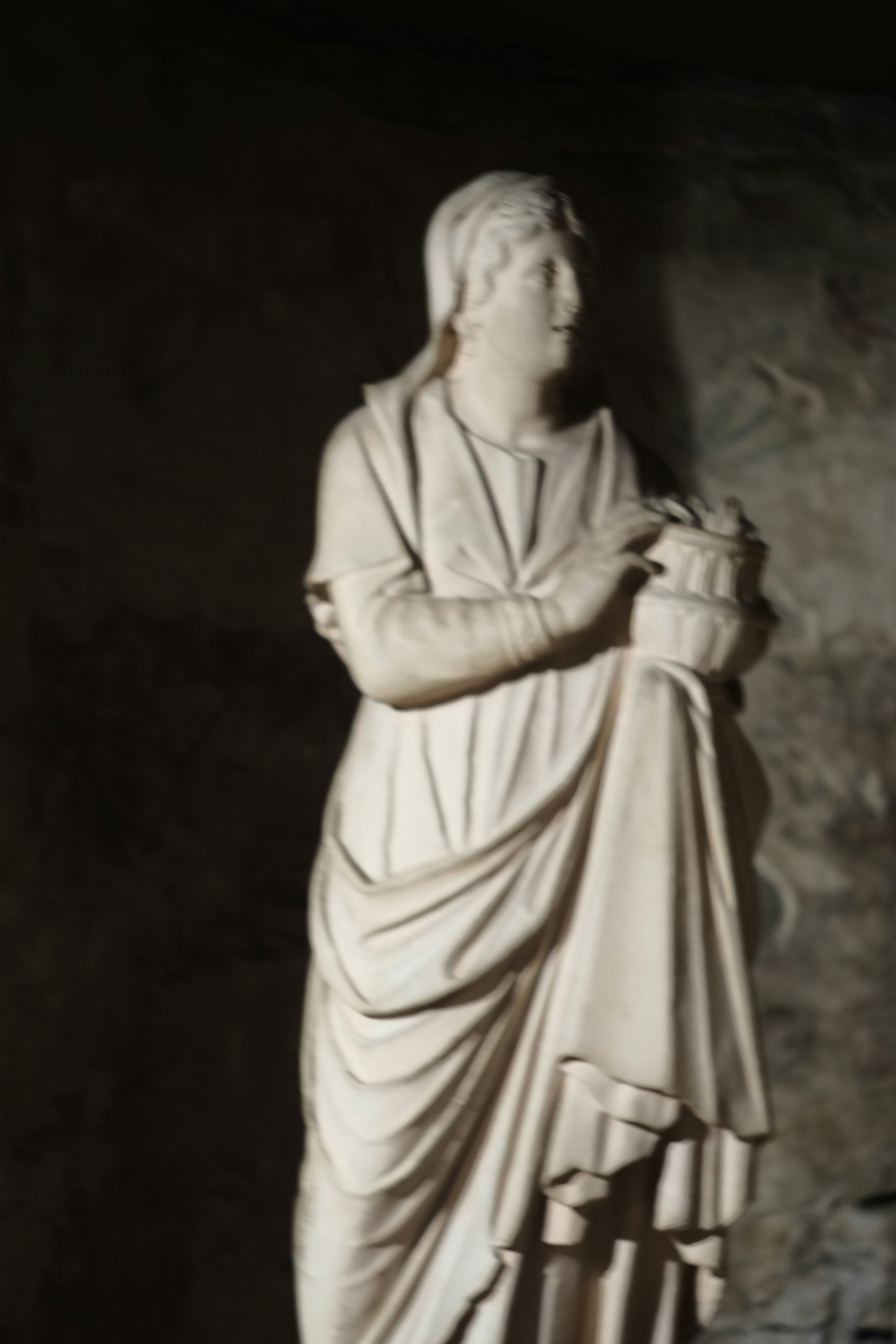 A white marble statue of a woman standing gracefully