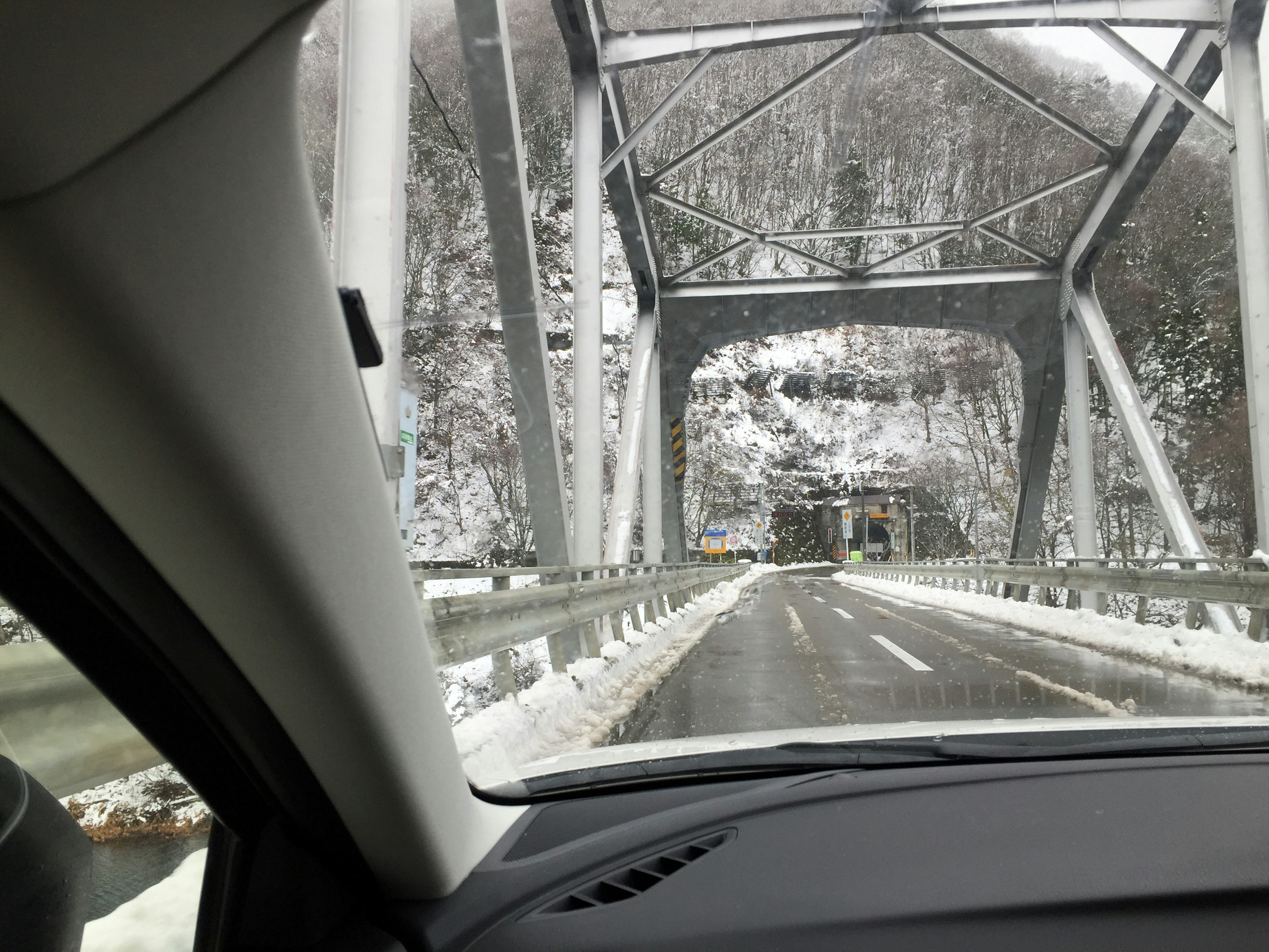 Inside view of a car driving under a snow-covered bridge