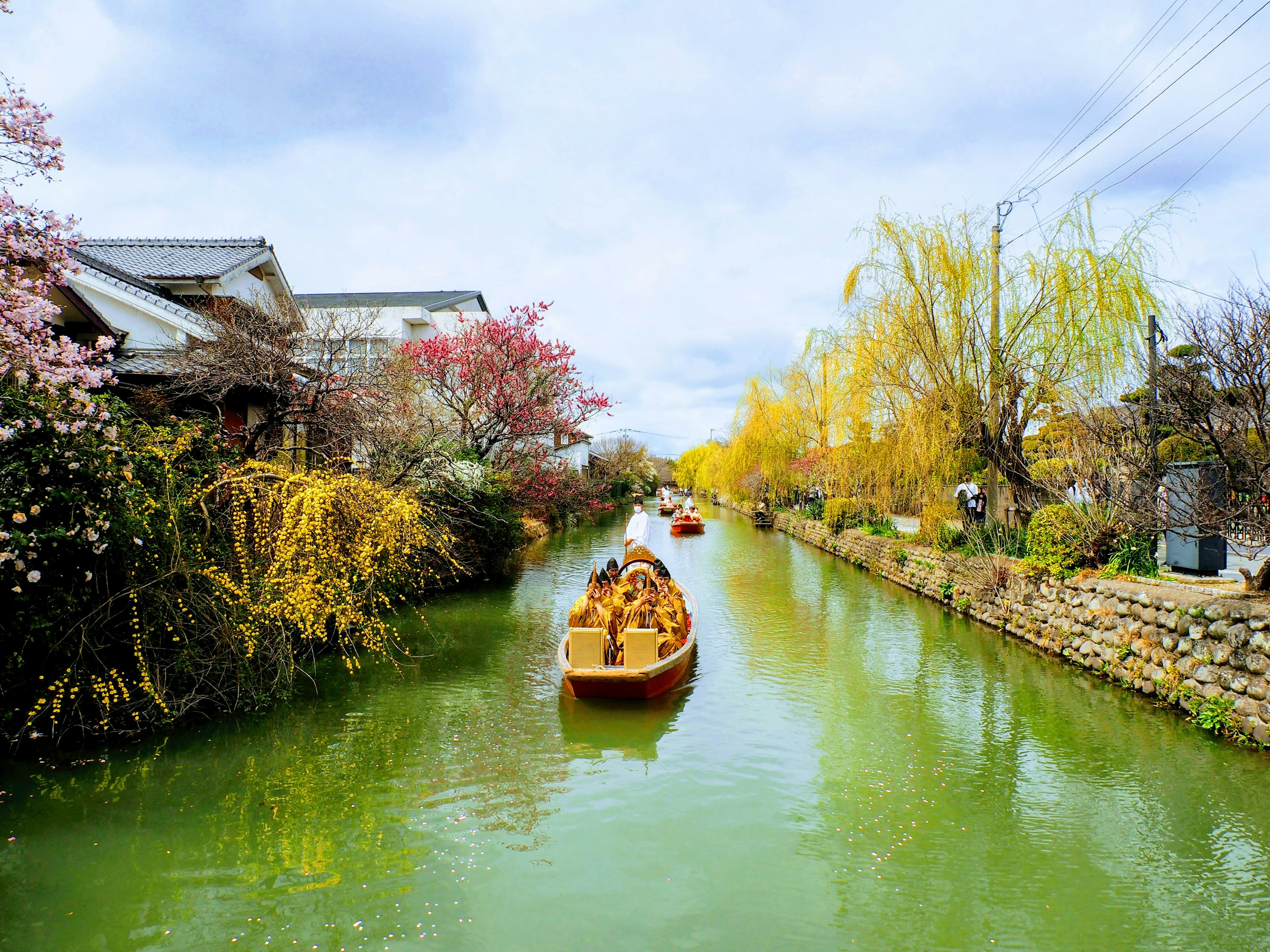 Boat gliding through a green canal surrounded by autumn foliage