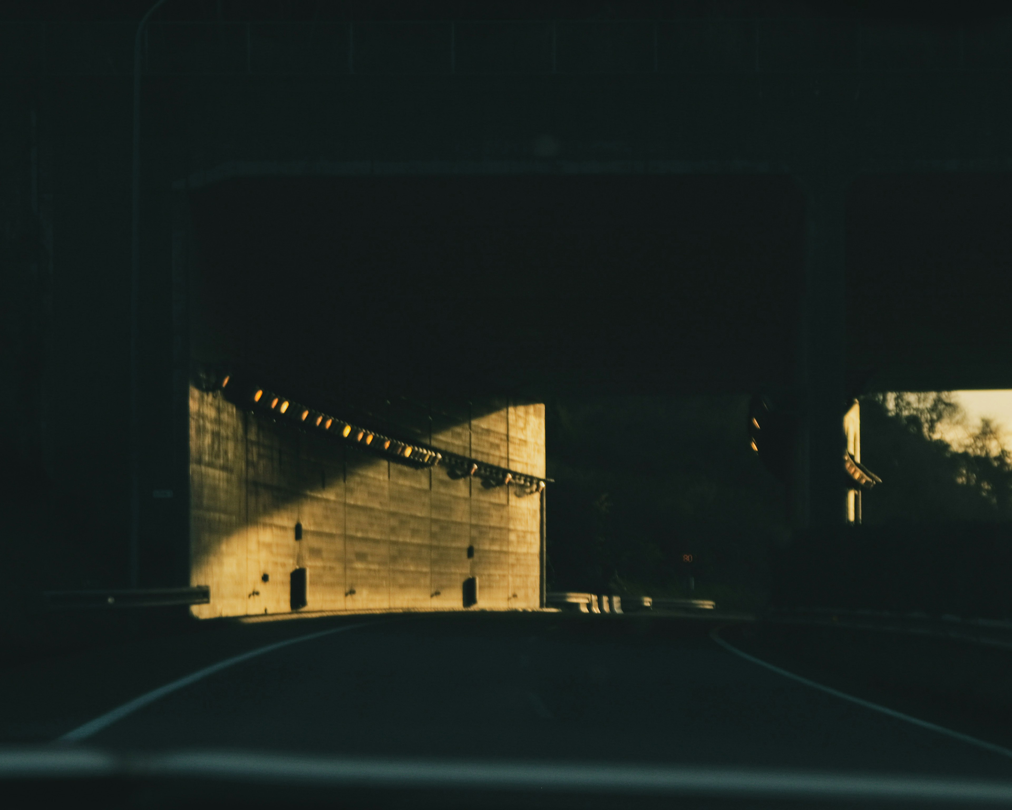 Imagen de una carretera que conduce a un túnel oscuro con luz brillante reflejándose en las paredes del túnel