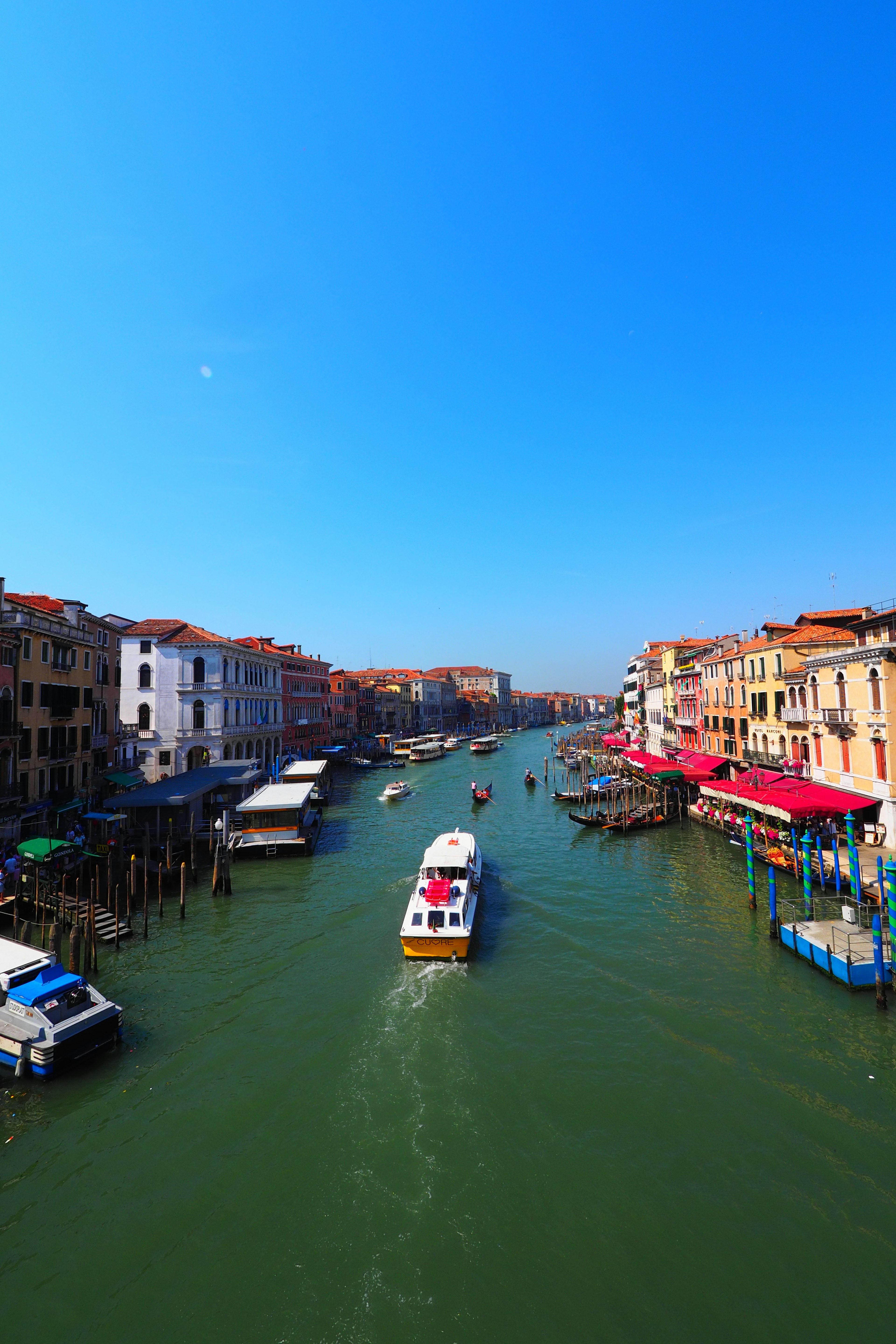 Boot, das einen Kanal in Venedig mit strahlend blauem Himmel befahren