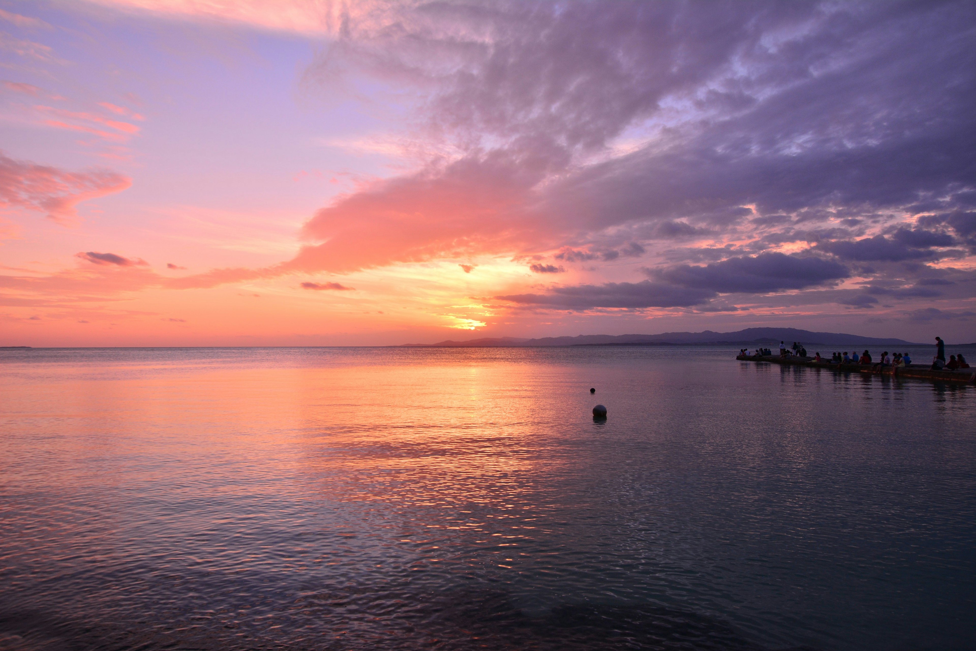 美しい夕日が海に映る風景で、空はオレンジと紫の色合いに染まっている