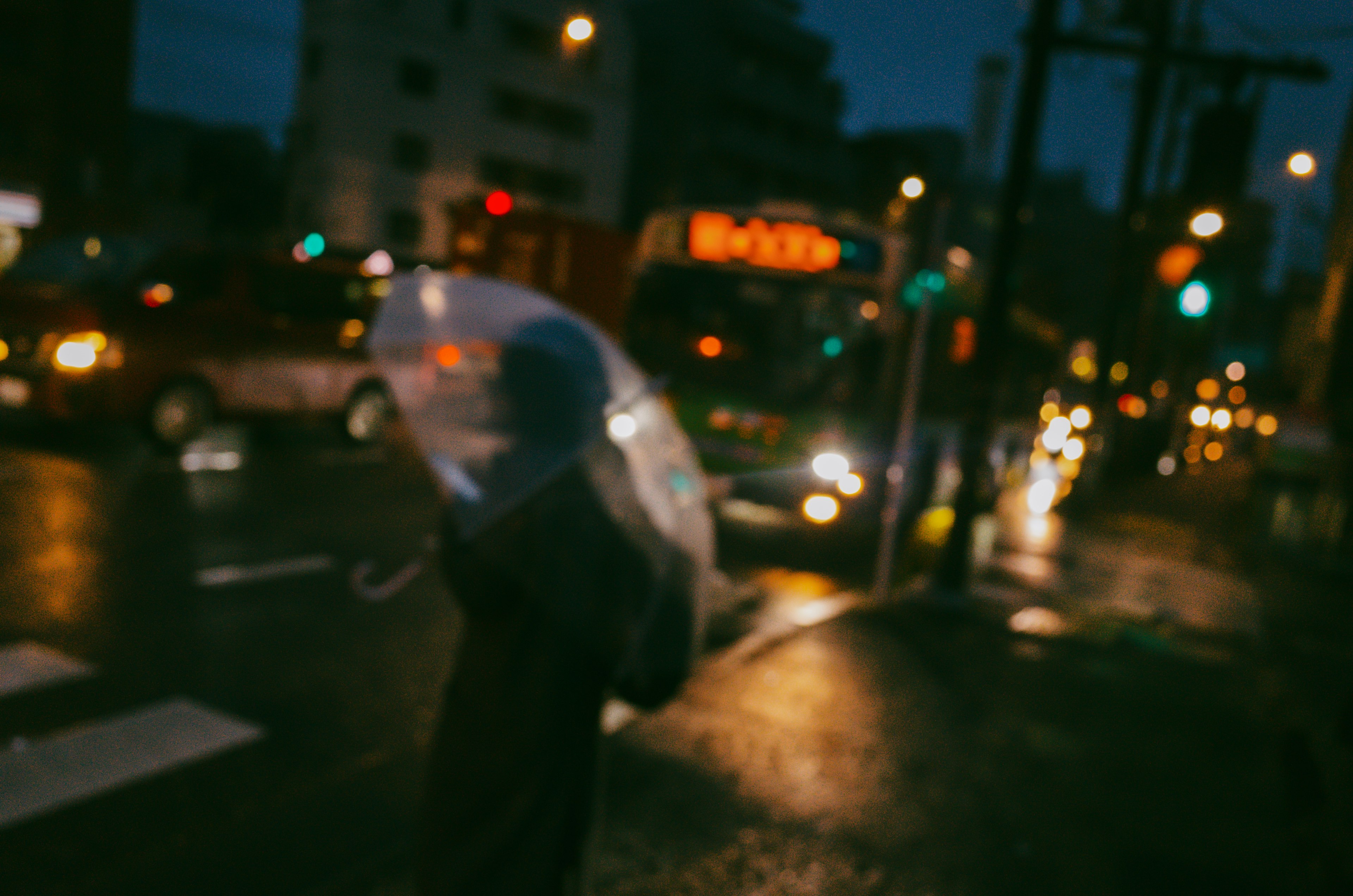 在雨中撐傘的人和模糊的車燈